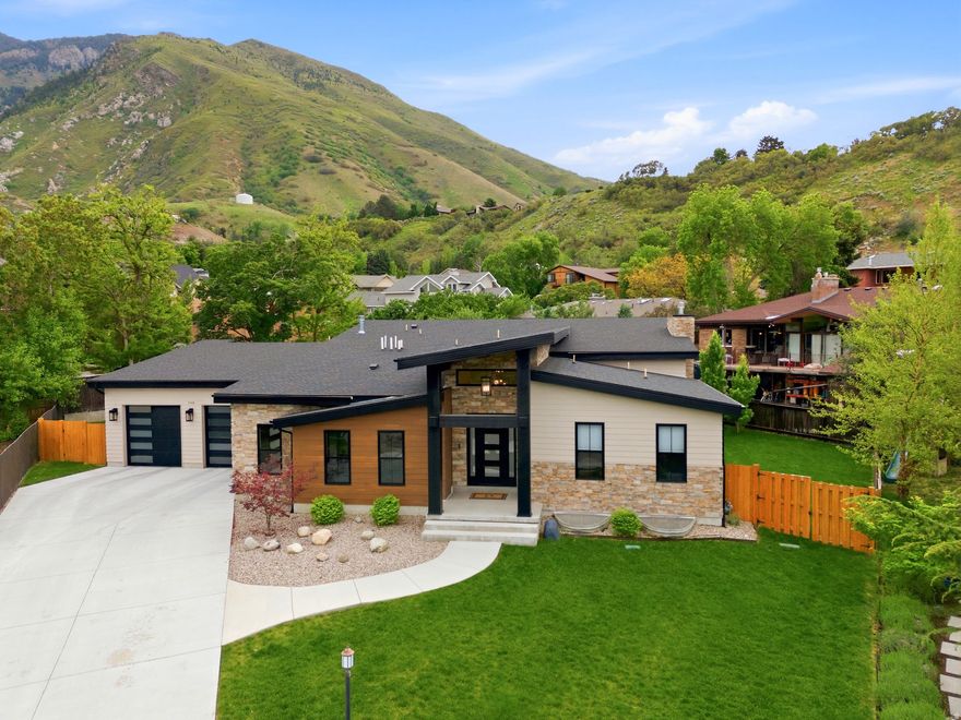 This striking modern custom home set against the foothills of the Wasatch in Cottonwood Heights is thoughtfully designed. Soaring vaulted ceilings, clerestory windows, and a dramatic floor-to-ceiling stacked-stone fireplace anchor the great room to a kitchen made for cooking and entertaining.  A butlers pantry makes entertaining effortless and keeps the main kitchen pristine. Built in 2022, it has both elegance and functionality in mind. Off the front entrance, find a perfect space for an office (or guest bedroom) with en suite.  Enjoy the large dining nook framed by canyon views through black-framed windows.  The master suite doesn't disappoint with its own views, large walk-in closet with bench and built-in shelving, oversized double headed shower and free standing tub.  The finished lower level is its own residence within the home: an expansive secondary great room with its grand kitchenette. More custom lighting, a black window package, another stacked stone fireplace, a 2nd laundry room, 2 junior suites and 2 additional bedrooms with a shared bath.  The oversized garages have customized epoxy floors. There is also a secured storage room with a vault door.  A rare opportunity to own a newer home in an established area desirable for being able to walk to restaurants and have easy canyon and freeway access.