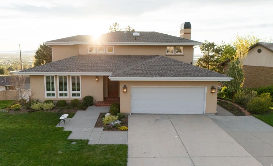 Perched high on the Bountiful bench, this home captures the kind of views - mountains, the Salt Lake Valley, and the Great Salt Lake - that define Davis County living. The kitchen, main living area, and several other spaces were masterfully redesigned and renovated by renowned architect Robert MacArthur, striking that rare balance between high-end sophistication and a home that feels genuinely comfortable. The chef's kitchen is the centerpiece, anchored by Wolf and Sub-Zero appliances, custom cabinetry with roll-outs, and polished cement countertops set against crackle-glazed subway tile. Solid white oak floors flow throughout the upper level, paired with custom wainscoting and a bespoke stair railing that showcases exceptional craftsmanship.  The primary suite is a quiet sanctuary, finished with custom plantation shutters and a marble-accented bathroom that stays bright and airy thanks to its skylight. The home's unique character continues with hand-painted details in the playroom by artist Susie Muise, who also put her touch on the custom double blinds on the main floor. Downstairs, the walk-out basement is built for entertaining, featuring a kitchenette, a home theater with an automatic projector screen, office space, and a gym (the equipment is included!).   The stunning exterior matches the interior's appeal, showcasing a beautifully landscaped yard that invites you to soak in the surroundings. Relax on the Trex deck and enjoy the lush greenery and captivating valley views, or spend quality time in your outdoor oasis, which perfectly complements the home's sophisticated aesthetic.  Beyond the high-end finishes, the home is incredibly well-maintained, featuring a newer AC and water heater, central vacuum, water softener, and a Speed Queen laundry set served by a classic laundry chute.  *Square footage figures are provided as a courtesy estimate only and were obtained from county records. Buyer is advised to obtain an independent measurement.*