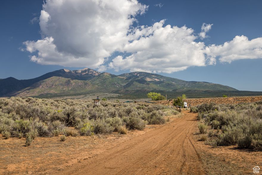 Bask in views of three mountain ranges from your campsite or custom home, the La Sal Mountains, the Abajo Mountains and the Henry Mountains. A dry pond bed and mature trees create an earth wall of privacy and protect your viewshed of the La Sal Mountains. There are many ways to enjoy this fully fenced 39-acre parcel. The gravel road from the gate leads to a campground with four established sites and a caretaker site that has rave reviews. Each site includes a fire pit, picnic table and shade arbors. There is also a pit toilet and trash receptacles. A sophisticated well house has 3200 watts of solar on the roof and there is currently enough power to expand to twenty sites. Seven acres of irrigated wildland grass encourage deer and other wildlife. The land is also subdividable, which creates even more options.