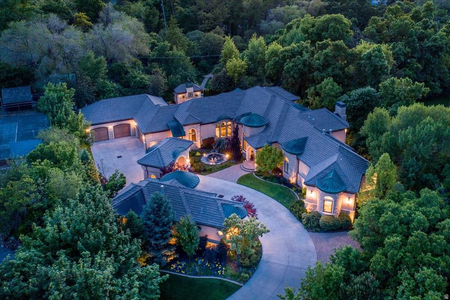 Tucked away on a private, tree-lined lane in Holladay, this resort-style estate offers rare privacy in a picturesque setting with an exceptional array of amenities. Situated on 1.15 acres with sweeping mountain views, this beautifully updated home blends timeless architecture with refined, modern living. The main level features an elegant living room, formal dining, and a stunning, well-appointed kitchen offering generous workspace, abundant cabinetry, and quality appliances, all flowing seamlessly into inviting gathering areas. A striking office with walnut ceilings, flooring, and woodwork.  The main-level primary suite is a peaceful retreat, capturing beautiful mountain views and featuring a spa-inspired bath, dual closets, glass-encased vertical flame columns and a private deck. Expansive retractable doors open to a spectacular outdoor setting with a saltwater pool with water features, spa, and outdoor BBQ area. The lower level features high ceilings, three spacious bedrooms, three baths, a theater, a home gym, a wine gallery, and a game lounge. A detached private guest house offers its own kitchen, family room with a two-sided fireplace, large bedroom, and spa bath, ideal for extended stays or private guest accommodations. Gated and impeccably landscaped, the grounds showcase stunning mountain views and a sense of seclusion, just minutes from shopping, dining, golf, and canyon access. Expertly constructed by Dan Stewart, Tri-City Construction.