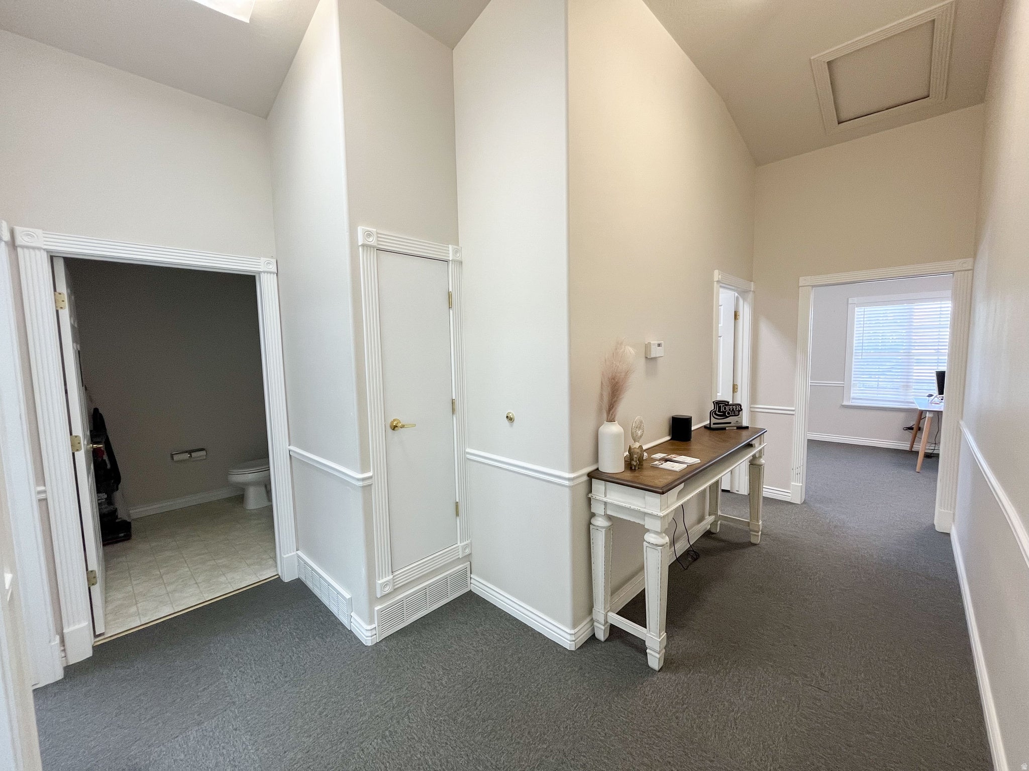 Central hallway with vaulted ceilings, recessed lighting, and wall paneling