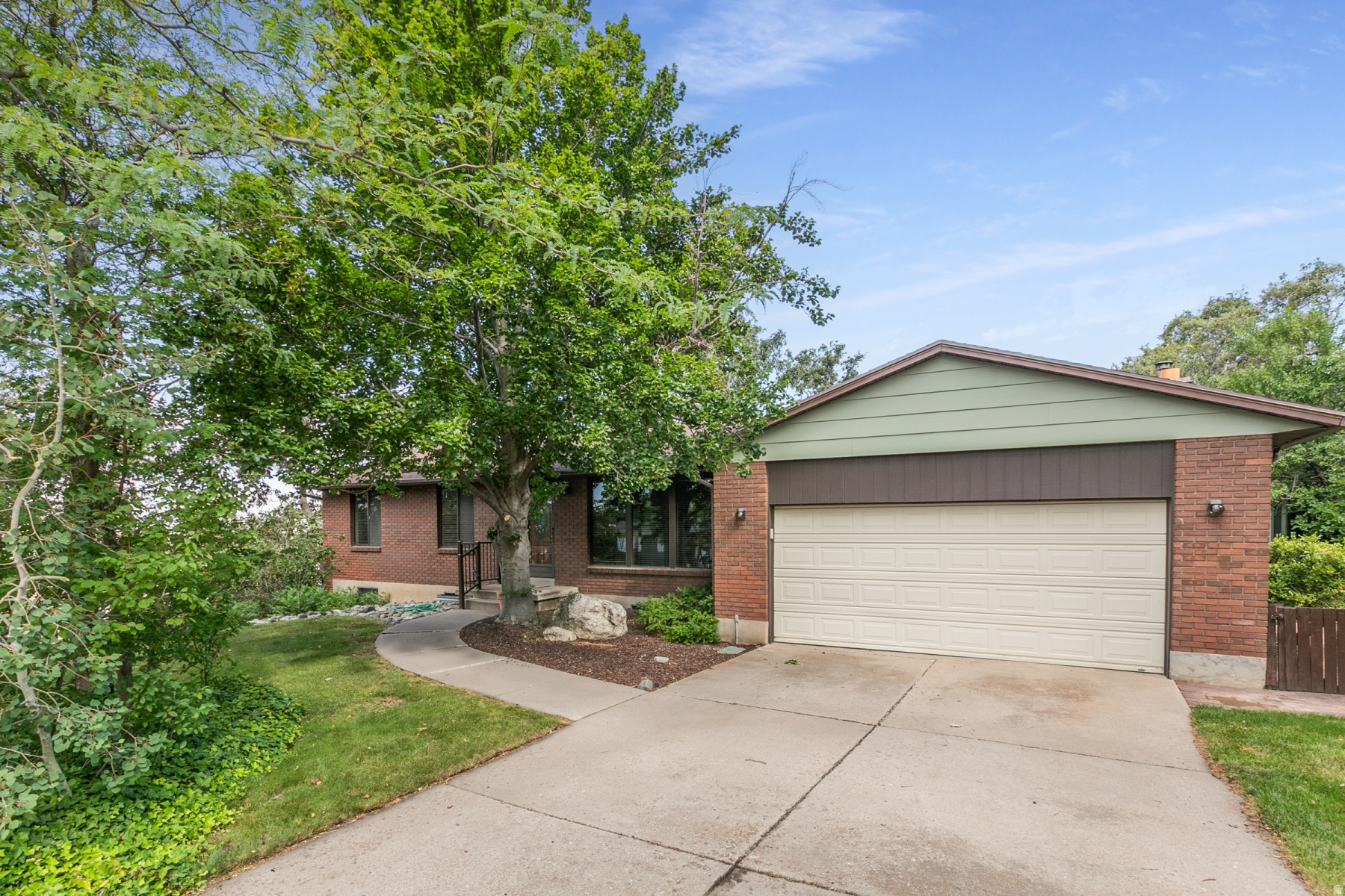 Brick exterior featuring a two-car garage and a concrete driveway
