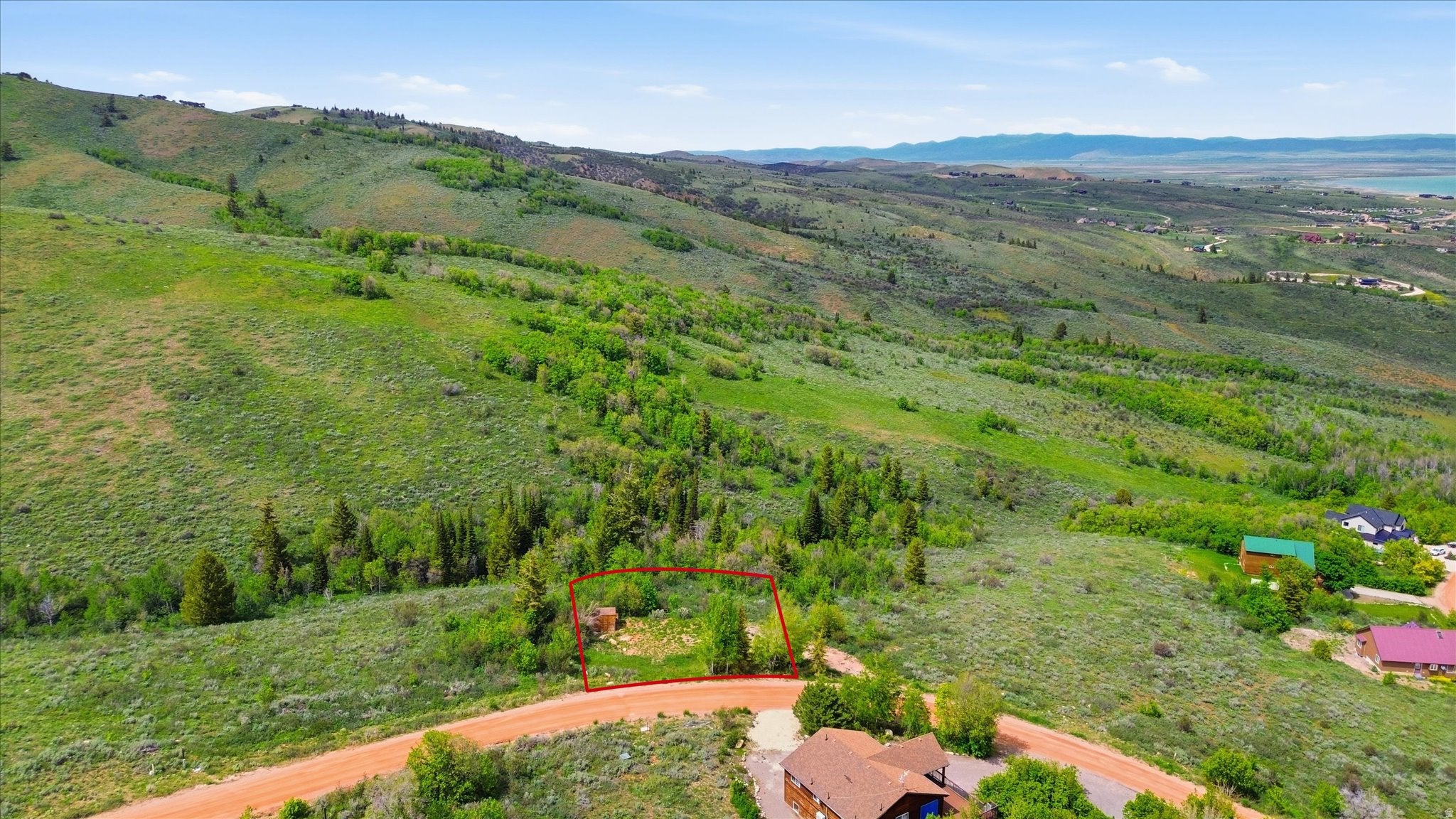 Expansive lot on a hillside with natural vegetation and distant water feature