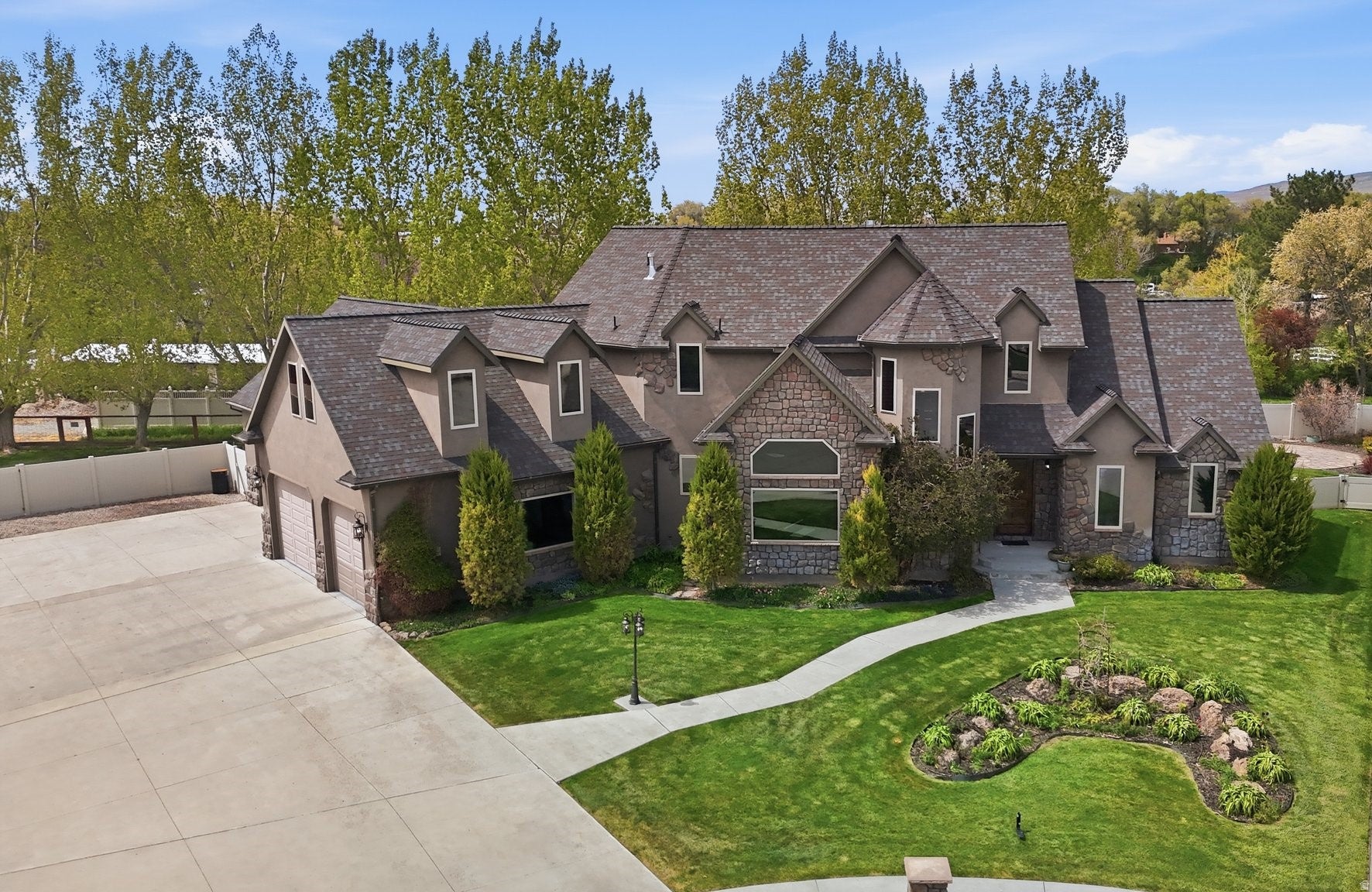 Multi-level residence featuring a stone and stucco exterior, a prominent gabled roofline, and dormer windows