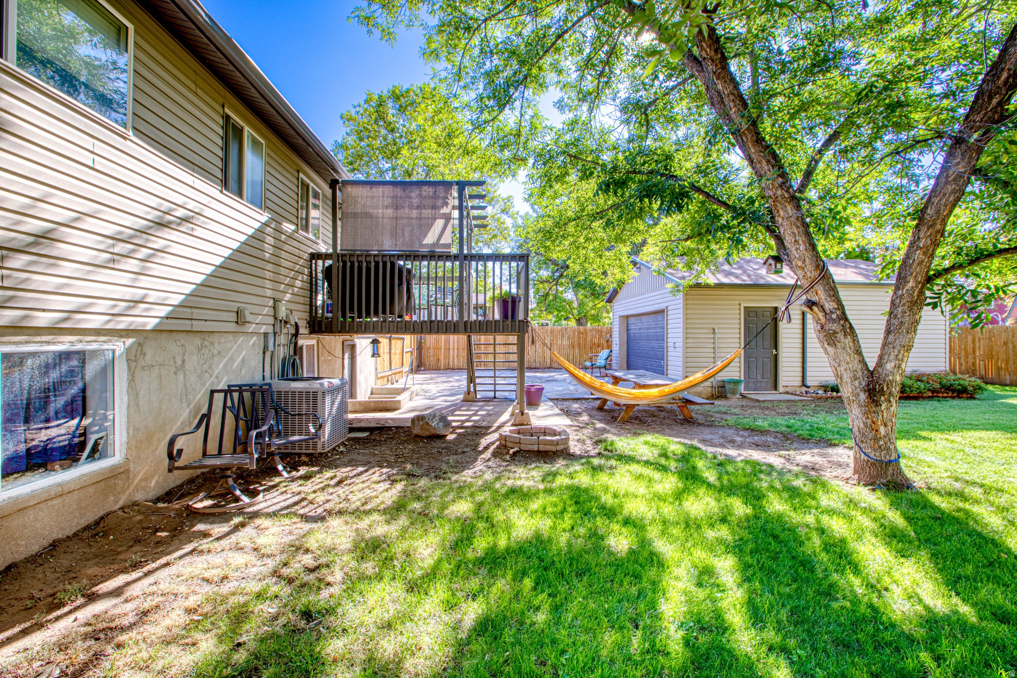 Backyard featuring a wooden deck, concrete patio, detached garage, and a fenced perimeter