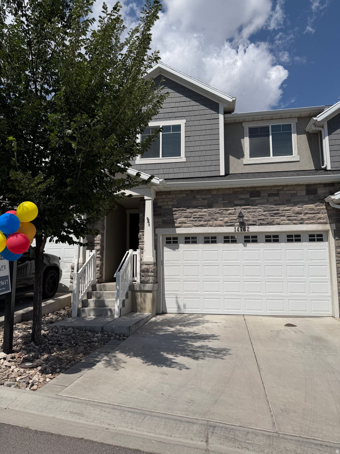 Contemporary multi-level residence featuring a two-car garage, stone fa?ade accents, and shaker-style siding