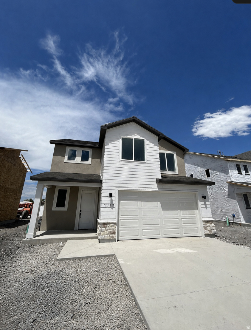 Contemporary two-story residence featuring a two-car garage, white siding, stone accent detailing, and a covered entry