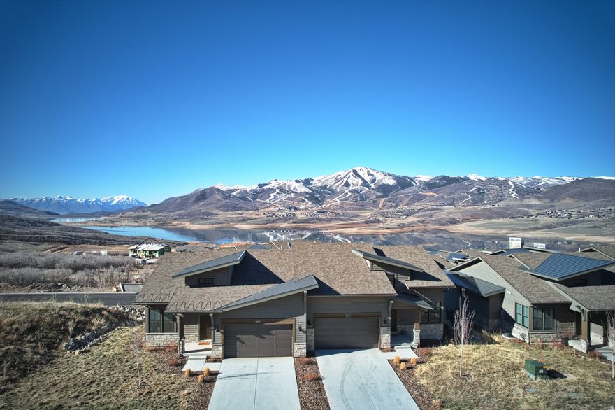 Discover the Park City lifestyle from this mountain modern retreat with ski-run, mountain and water views. A thoughtful and meticulous attention to design & function went into the selection of numerous additional high-end upgrades for this main-level living townhome. Upgrades include extra-large primary bath with dual-vanities, striking floor to ceiling, sintered stone-slab fireplace face in the great room, kitchen/dining area lighting, fixtures, and Bosch stainless-steel appliances, built-ins on both levels, automatic blinds, and garage finished with epoxy floors and EV charger. Enjoy walk-out lower level with hot tub, large family/game room with dry bar and beverage fridge, 2 spacious bedrooms and 2 full baths. Recessed lighting throughout, high ceilings throughout and lots of natural light. Central AC, heat tape, tankless water heater. Ample guest parking adjacent to this end unit.  Enjoy the Jordanelle State Park directly adjacent with access to trails, beaches, cabanas, bathrooms, perfect for walking dogs, paddle boarding, swimming, and canoeing. Quick access to skiing, shopping, dining, Park City and the airport. And nearby Richardson Flat Park & Ride connects to 3 main Park City Transit express routes, giving riders direct service into town and to ski resorts.