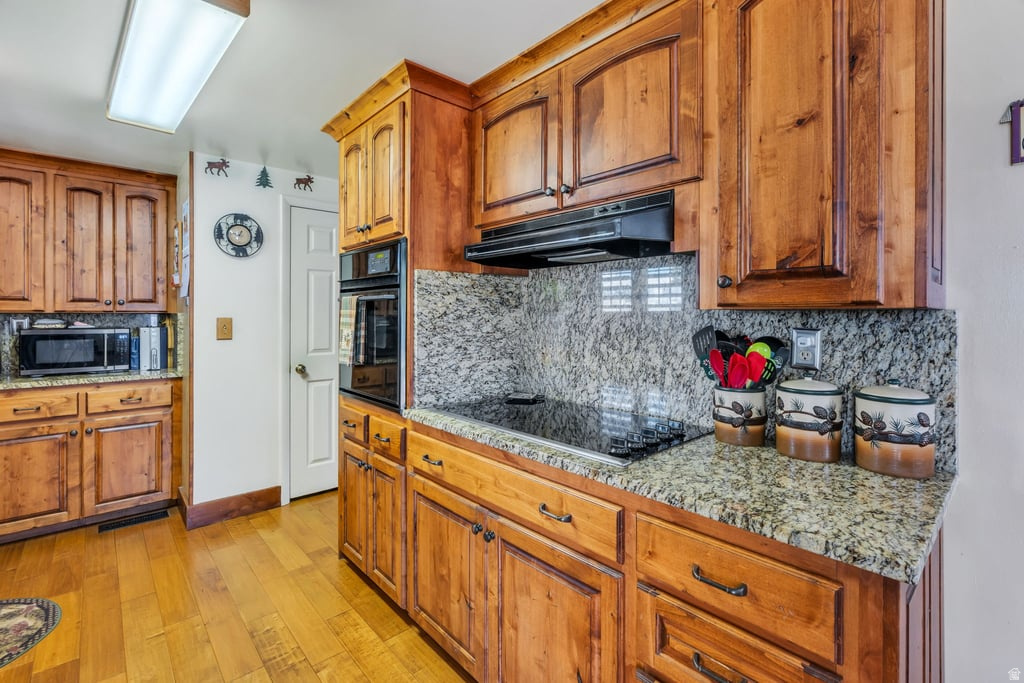 Kitchen featuring wood cabinetry, granite countertops, and a smooth cooktop