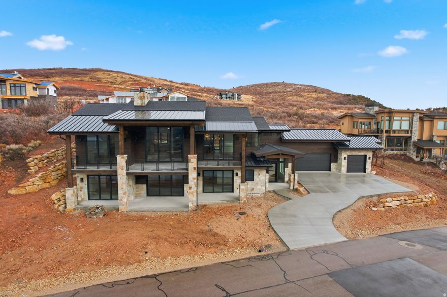 This brand new luxury build is perfectly seated on the lower hills of Golden Eagle to capture epic and inspiring views of Deer Valley ski runs and the peaks of Timpanogos, as well as the Jordanelle reservoir.  This classic mountain luxury style home is built with elevated style and effortless function at its core. An oversized three car garage and grand driveway sets the stage for an elegant exterior with massive patios and decks to take in panoramic mountain vistas.   The lower level has three large bedrooms with walk-out patios and a versatile living space that can accommodate a tv lounge with an adjoining alcove for a billiards room or library. A bespoke laundry room with colorful accents and beautiful stone rounds out this level, perfect for entertaining guests with comfort and privacy.  The foyer features an elegant stone wall that follows the staircase to the main level. Every detail is thoughtfully crafted from beautiful stone basins in the powder bath, to hand picked quartzite slabs and light fixtures. The main level opens up to massive mountain views flooding the house with light and natural beauty. Large glass doors slide all the way across to provide indoor-outdoor living from the main room. The gourmet kitchen has custom walnut cabinetry with Thermador appliances, and double ovens. The grand focal point of this sunny living space is a floor to ceiling fireplace that tastefully grounds the room in a cozy and elegant atmosphere.   Off the main room is a beautiful office space with French doors, and further down you enter the primary bedroom with stunning deer valley views and private balcony access. A stone fireplace, gorgeous oversized bathroom with a soaking tub, beautifully tiled shower and walk-in closet complete this luxurious primary suite.   Rounding out the home exterior is a large back patio space for quiet nights under the stars, perfect for outdoor dining or soaking in the hot tub. As one of Golden Eagle's most desirable gems, this home is fully complete and ready to welcome you home to the most stunning views in Utah.