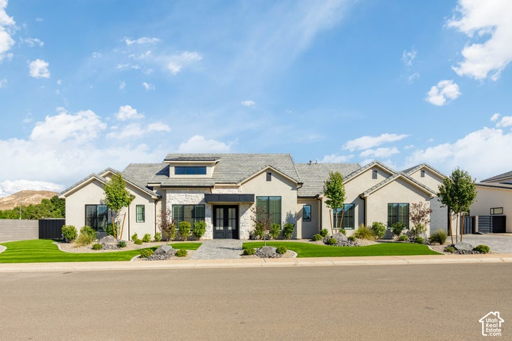 Stucco exterior with stone accents, black-framed windows, a double entry door, and a paved driveway