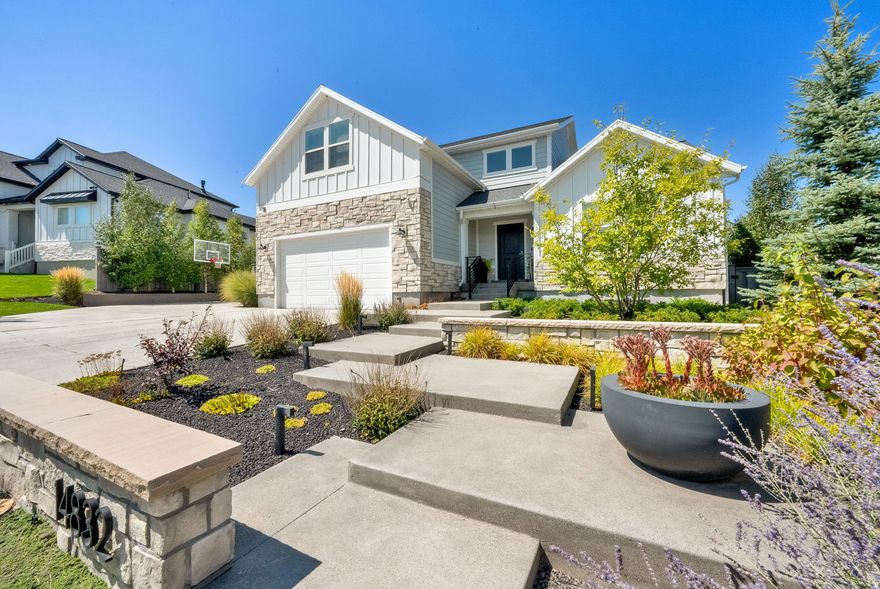 Beautifully designed home, set on a spacious .83 acre lot, offers exceptional curb appeal and breathtaking mountain views. The inviting exterior leads into a light-filled interior with large windows throughout, creating a warm and welcoming atmosphere. The stunning kitchen is a true showpiece, featuring crisp white cabinetry accented with rich blue cabinets, a massive center island, quality finishes, and ample workspace-perfect for entertaining and everyday living. The kitchen flows seamlessly into the open great room, highlighted by a dramatic floor-to-ceiling fireplace and an expansive open-concept design. A main-floor den provides ideal space for a home office. The primary suite is a peaceful sanctuary with a luxurious ensuite bath, complete with a double-sink vanity, separate soaking tub and shower, and a large walk-in closet. Upstairs, you'll find three generously sized bedrooms, a full bath, and a versatile bonus room perfect for a playroom, media space, or additional lounge area. The fully finished lower level expands the living space with a spacious family room, two additional bedrooms, and a full bath, plus a separate, fully finished storage area. Step outside to enjoy an exceptional outdoor lifestyle with multiple patios designed for relaxation and entertaining. The property features a hot tub, outdoor grill area, and radiant-heated walkway for year-round access. Meticulously landscaped grounds include approximately 70 mature and ornamental trees, lush groundcovers, vibrant perennial flowers, ambient outdoor lighting, a charming garden shed, raised garden beds, and recreational features including a trampoline and a play structure with swings and climbing areas. This remarkable home offers privacy, space, and luxury-perfectly blending refined indoor living with extraordinary outdoor amenities. AND... extra parking, EV Charger and a Basketball Hoop, too!  It's a GEM!