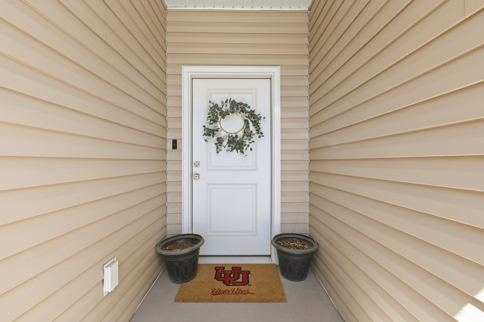 Recessed entry featuring a white paneled door, light-colored horizontal siding, and a concrete porch