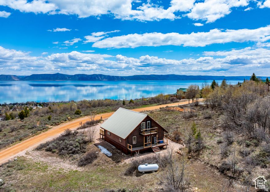 Darling updated log cabin on large .60-acre lot, your private escape near the top of main Bear Lake West overlooks the clear blue waters of beautiful Bear Lake. New stain and chinking on exterior, updated electrical, flooring, paint, new appliances in 2024, and pellet stove for your cozy retreat. Lot backs up to common area at the mouth of Williams Canyon. Bear Lake West amenities include beach access, tennis/pickleball court, swimming pool, plus golf and restaurant within minutes. Access to hundreds of miles of snowmobiling trails close by! Beaver Mountain Ski resort 30 minutes, Bear Lake Marina 15 minutes. For a glorious respite, this cabin will be your haven for all seasons  No short-term-rentals.