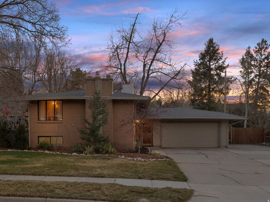 Tucked into the quiet Willow Creek neighborhood of Sandy, this beautifully updated home offers the perfect blend of comfort, style, and an unbeatable Utah lifestyle. Surrounded by peaceful streets and stunning mountain views, you'll love the close proximity to Willow Creek Country Club, neighborhood parks, top-rated schools, shopping, dining, and the world-class skiing of the Cottonwood Canyons, making every season an adventure. Situated on a rare .31-acre lot with an oversized driveway and RV parking, this property offers exceptional space for recreation, hobbies, and hosting alike. The stylish brick exterior carries a timeless mid-century vibe that sets it apart in the neighborhood. Inside, the bright main level welcomes you with an open floor plan designed for both everyday living and effortless entertaining. The spacious great room is anchored by a cozy fireplace with a stone hearth, custom mantel, and designer floating accent shelves. The adjacent gourmet kitchen is beautifully appointed with custom cherry cabinetry, double ovens, a center island, and stainless steel appliances - thoughtfully designed to be both functional and inviting. From the dining area, step outside to an expansive deck overlooking the park-like backyard, complete with a lush lawn and generous patio space ideal for gatherings. The yard is fully fenced and enhanced with an automatic sprinkler system, garden boxes, manicured landscaping, and mature trees that create privacy and charm. The flexible layout offers two upstairs bedrooms and three additional lower-level bedrooms, along with two remodeled bathrooms. Paid-off solar panels provide energy efficiency and long-term savings, while a roof replacement in 2020 and an updated HVAC system offer added peace of mind. Move-in ready and thoughtfully upgraded throughout, this exceptional home seamlessly combines indoor comfort, outdoor living, and convenient access to Sandy's best recreation and amenities.