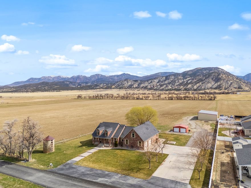 This home is exactly what you have been looking for. Perfectly positioned on just over 1 acre with unobstructed views of Mt. Nebo to the north and breathtaking mountain views surrounding the back of the property. Bordering open farmland, the setting offers peaceful country living with wide open space, quiet surroundings, and scenery that changes beautifully with the seasons.  This all brick farmhouse rambler was designed for comfortable living and memorable gatherings. A covered patio creates the perfect place to start the day, watching the sun rise over the mountains while taking in the calm and beauty that surrounds the home.  Inside, the main floor welcomes you with an open layout and vaulted ceilings that create a bright, airy feel throughout the living spaces. Large windows bring in natural light and showcase the surrounding views. The kitchen is thoughtfully designed for both everyday living and entertaining, featuring granite countertops, a high end range with water pot filler, double ovens, a food compactor, and even towel and plate warmers.  The primary suite offers a private retreat with its own walkout to the covered patio. The ensuite bathroom features a jetted tub, an oversized granite surround shower, and a gas fireplace that adds warmth and a touch of luxury, creating the perfect place to unwind at the end of the day.  Downstairs, the basement features impressive 10 foot ceilings, multiple storage rooms, and a second kitchen that makes hosting guests or accommodating extended family easy and comfortable. A private movie theater with drop down steps adds a fun and memorable feature, perfect for movie nights or watching the big game.  Above the garage, a bonus room with skylights fills the space with natural light, creating a bright and versatile area that could serve as an office, studio, playroom, or additional living space.  For added comfort and efficiency, the home is heated and cooled with two geothermal pumps, allowing for reliable and customizable year round comfort.  Homes offering this kind of setting, space, and thoughtful design rarely come available. With stunning views, peaceful surroundings, and room to live and gather, this truly is a one of a kind property ready to welcome its next chapter. Additional land may be able to purchase.