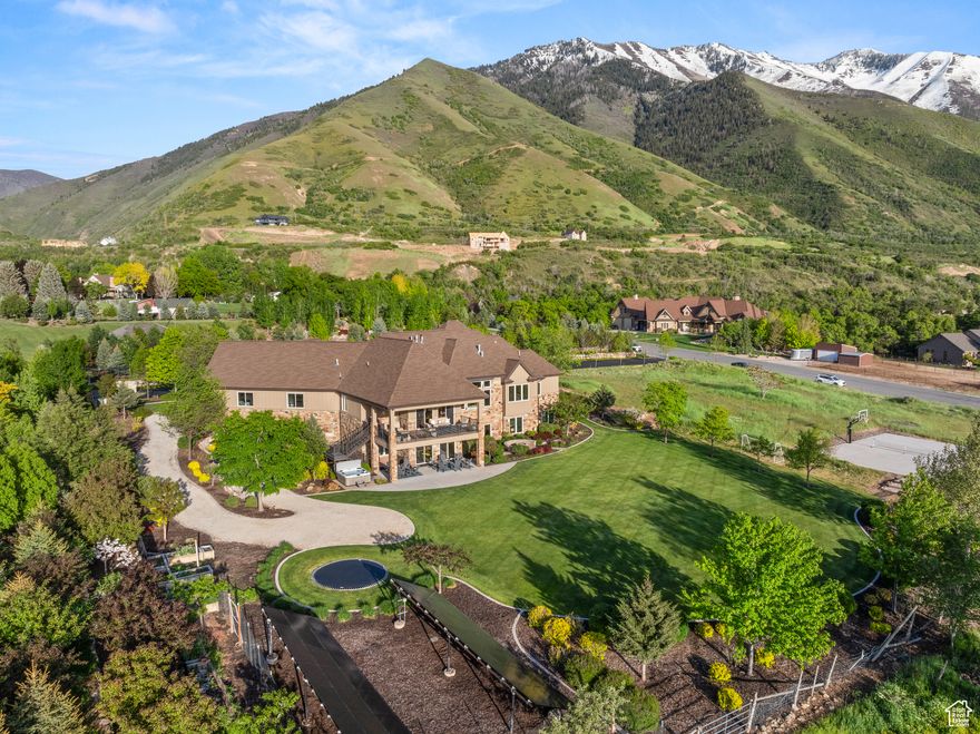 Experience unparalleled luxury in this stunning custom rambler set on 2 acres with sweeping views of Utah Lake, Maple Mountain, and Mt. Nebo. This 6,000+ sq ft masterpiece offers true single-level living with a main-floor primary suite, private office, spacious great room, and zero-step entry for full ADA accessibility. Enjoy soaring 1013' ceilings, walls of windows, and a full Control4 smart home system. The gourmet kitchen is a chef's dream, featuring a 60" Wolf range, Sub-Zero refrigerator, hidden pantry, oversized slab island, and beautifully crafted custom cabinetry. The walkout basement is perfect for entertaining with a large rec room, fireplace, surround sound, and a private guest suite. Additional highlights include a finished 3-car garage plus shop with hanging slab, 42 solar panels, whole-house audio, security, and water filtration systems. Step outside to your own resort-style retreat complete with a pickleball/basketball court, in-ground trampoline, hot tub, and mature trees. Includes animal and water shares (6.4 acres). The property also offers potential to subdivide. With far too many upgrades to list, this home is truly a must-see.