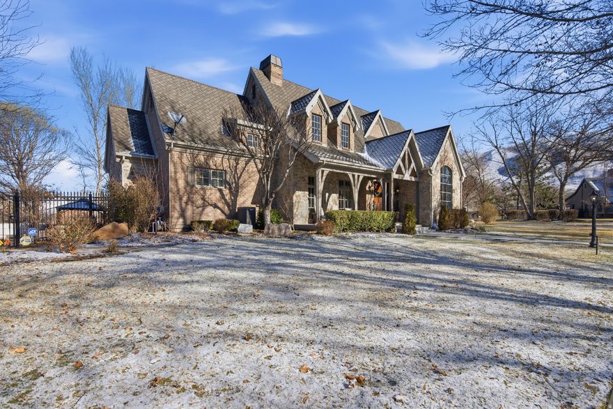 Nestled on one of Draper's most enchanting tree-lined canopy streets, this extraordinary estate sits on a private 0.61-acre lot-the crown jewel of the neighborhood. The hand-crafted brick and real stone exterior, solid Brazilian cherry wood flooring, Marvin wood-clad windows, and exquisite architectural details exemplify timeless, curated craftsmanship. The open-concept design features a two-story great room with a 30-foot real stone fireplace and wood-beamed ceiling. The gourmet kitchen offers informal dining, granite countertops, a new Thermador range, hood, and oven, plus a walk-through butler's pantry leading to a formal dining room. A spacious theater room on the lower level adjoins a kitchen, ideal for entertaining. The home offers unmatched flexibility with seven bedrooms, including four en-suite baths, two main-floor powder baths, three family rooms, a large craft/wrapping room, three storage rooms, and a private multi-desk office with built-ins. The main-level primary suite features an en-suite bath, a large walk-in closet with built-ins, and an island with locking jewelry drawers. French doors open to private, shaded outdoor dining and a serene backyard with a spa-like retreat. Additional features include solid wood four-inch shutters, three fireplaces, three air conditioners, and four furnaces that maintain consistent temperatures, an ADT security system, and nine-foot basement ceilings. The heated four-car garage includes two EV outlet plugs. Six French doors open to the backyard, allowing you to enjoy seamless indoor-outdoor living. Main-floor and lower-level laundry rooms offer added convenience. The backyard provides privacy with an eleven-foot-deep saltwater pool, a peaceful babbling stream, and shaded dining under a pergola with views of a five-acre ranch filled with horses and wildlife. Two water shares offer secondary water to complete this exceptional property. This estate offers a lifestyle of elegance, comfort, and natural beauty in one of Draper's most coveted neighborhoods.. Square footage figures are provided as a courtesy estimate only and were obtained from County Records.  Buyer is advised to obtain an independent measurement.