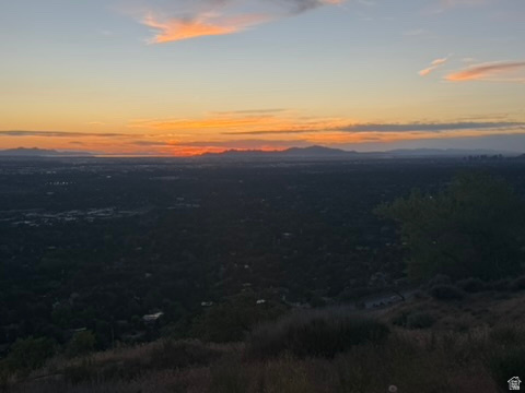 Panoramic landscape featuring distant city lights under a vibrant sunset sky