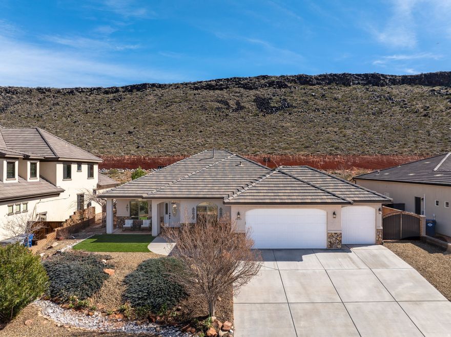 **PRICE REDUCED**Located in Dixie Springs just 7 minutes from Sand Hollow Lake & the dunes, this 4-bedroom home offers elevated finishes, flexible living space, & beautiful mountain views while backing to a stunning natural hillside. The layout includes a versatile bonus/flex space ideal for a home office, gym, media room, or hobby area. The third-car bay has been enclosed to create additional usable space while maintaining a functional two-car garage. Open kitchen features quartz countertops, a large contrasting island, white cabinetry w/crown detail, updated pendant lighting, black hardware & fixtures, pantry storage & stainless appliances. The living room centers around a fireplace with built-ins and flows seamlessly into the dining area w/abundant natural light. The primary suite offers a spacious walk-in closet and an upgraded bath w/dual vanities, quartz counters, matte black fixtures, custom cabinetry storage, and a beautifully tiled walk-in shower w/bench seating. The backyard is a true highlight - professionally designed with artificial turf, mature palms, a tranquil rock water feature w/fountain, gazebo seating area & multiple entertaining spaces. Backing and siding natural hillside, the property provides exceptional privacy along w/expansive desert & mountain views that are difficult to find in this price range. Located on Dixie Power and positioned near boating, golfing, off-roading, hiking & all the recreation Sand Hollow is known for, this home offers comfort, flexibility, and lifestyle in one of Southern Utah's most desirable neighborhoods. 3rd car garage modified to a bonus flex room w/bathroom - not included in square footage.
