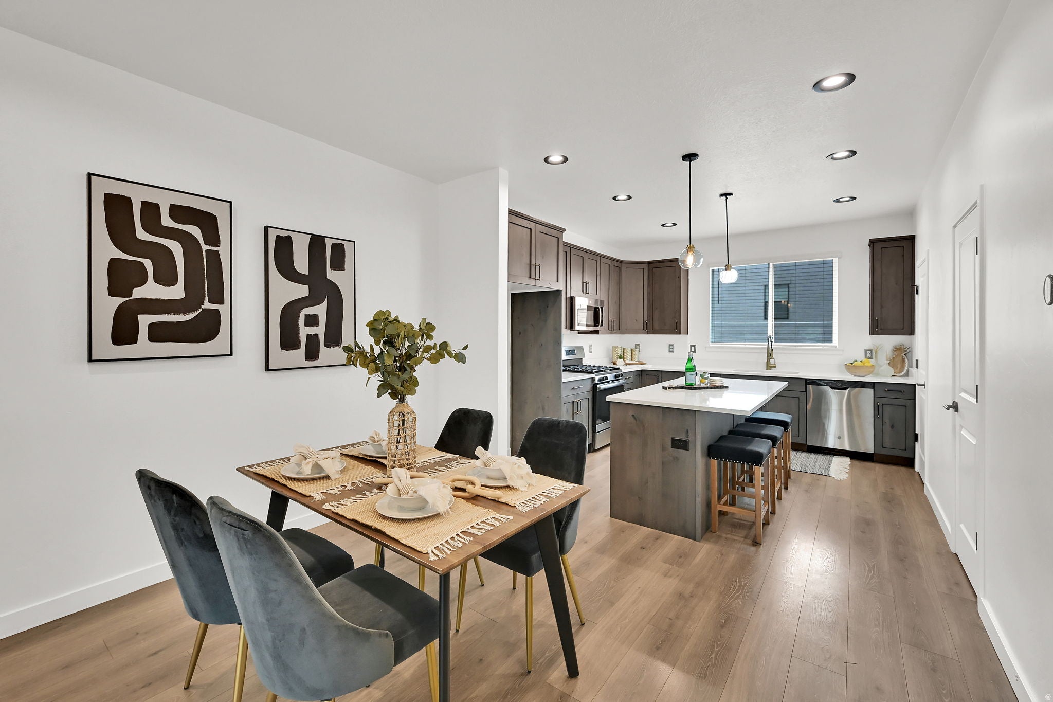 Open-concept living space with wood-finish flooring, recessed lighting, and a kitchen featuring a center island, stainless steel appliances, and ample cabinetry