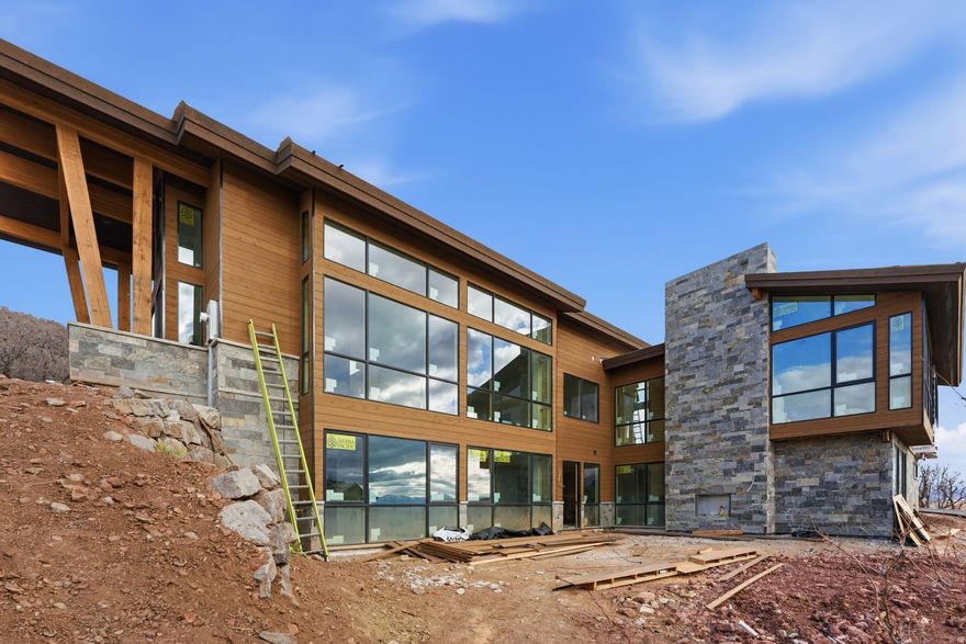 Sleek Modern Mountain Escape with Walls of Glass and Scenic Deer Valley Outlook from Golden Eagle. Host friends and family at a dinner table that looks out of floor to ceiling glass at the iconic resort views of Deer Valley from this brand new Golden Eagle home. Perched on a spacious 0.57 lot with almost all of the surrounding homes built near completion, your view corridors are clear and guaranteed from this stunning modern mountain home. Currently under construction, the residence is being crafted with an emphasis on sleek transitions, natural materials, and an abundance of glass that seamlessly blends indoor and outdoor living. Bask in sweeping Deer Valley views from a grand living room on the main level that features soaring ceilings and glass walls thoughtfully designed to capture the surrounding beauty. The home boasts four luxury bedrooms, each with en suite bathrooms offering comfort, privacy, and breathtaking vistas. The Main level primary combines a spacious bedroom with a built in fireplace, walk-in closet, and luxury bathroom with a free standing soaking tub. A state of the art kitchen includes top of the line luxury appliances and gorgeous slab counter tops. Oversized pantry and laundry rooms complete the easy of convenient living all on your main level. The lower level features two large bedrooms and a secondary living room with floor to ceiling glass out onto the patio. The top level offers a flexible private space with a fourth bedroom, office space, and additional large storage room. Multiple walkout patios extend the living space outdoors, perfect for entertaining or simply enjoying the serenity of the alpine landscape. Whether it's sunrise coffee on the upper terrace, or sunset gatherings around the fireplace on the expansive lower patio, this home invites you to immerse yourself in the serenity of mountain living from every angle.