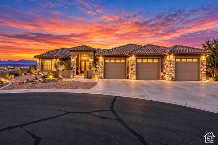 Stone facade with a tile roof, three-car garage, and desert-style landscaping