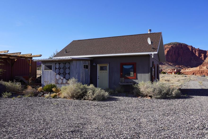 Wonderful in its simplicity and diversity, this Sleeping Rainbow property can be used in many different ways. Perfectly comfortable and enjoyable as it is, the cabin works well as a recreational retreat. Delightful with outstanding views and lovely outdoor space, and with this 2.37-acre lot, there is room to expand. If an owner chooses, more square footage could be added to the current structure, or it is possible to build another home and keep this one as a guest house. The 538 square foot cabin has ideally spaced and sized windows for the marvelous views. A wood burning stove and electric wall heaters sufficiently heat both rooms. A sizeable sleeping loft is included in the square footage. A Conex container placed on the west serves as storage and a wind break, and frames the pleasurable outdoor sitting area. The large lot affords a nice sense of space and privacy. It is stupendous in summer and fall. Close to miles of public lands for terrific hiking. Within walking distance to Torrey's Main St.