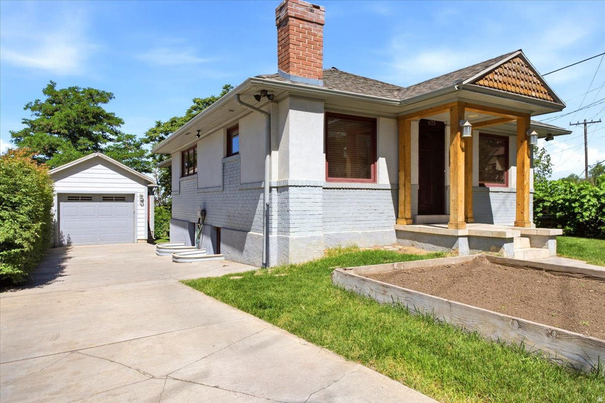 Split-level residence featuring a prominent brick chimney, an attached carport, and a detached two-car garage