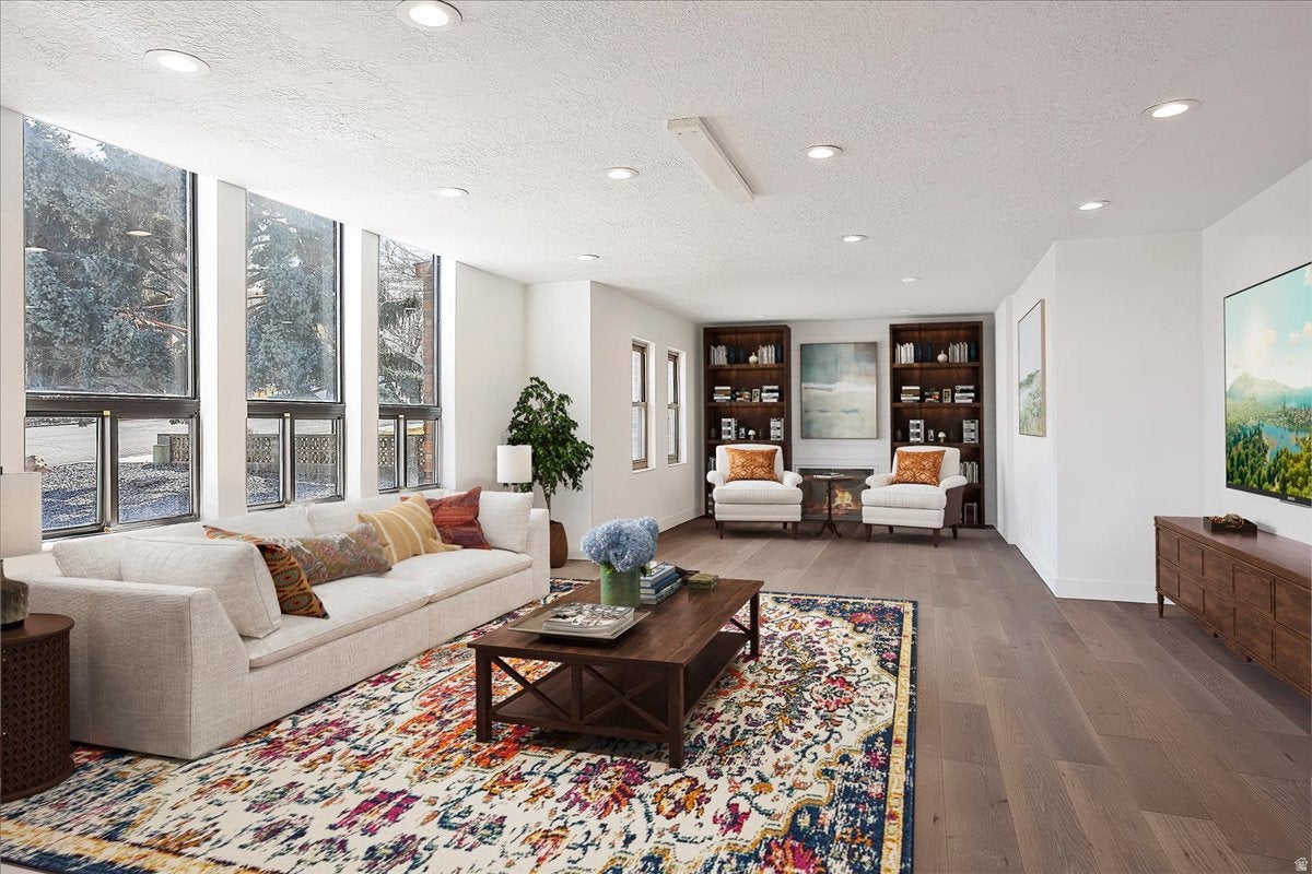 Open-concept living space with expansive windows, recessed lighting, wood-finish flooring, and built-in shelving