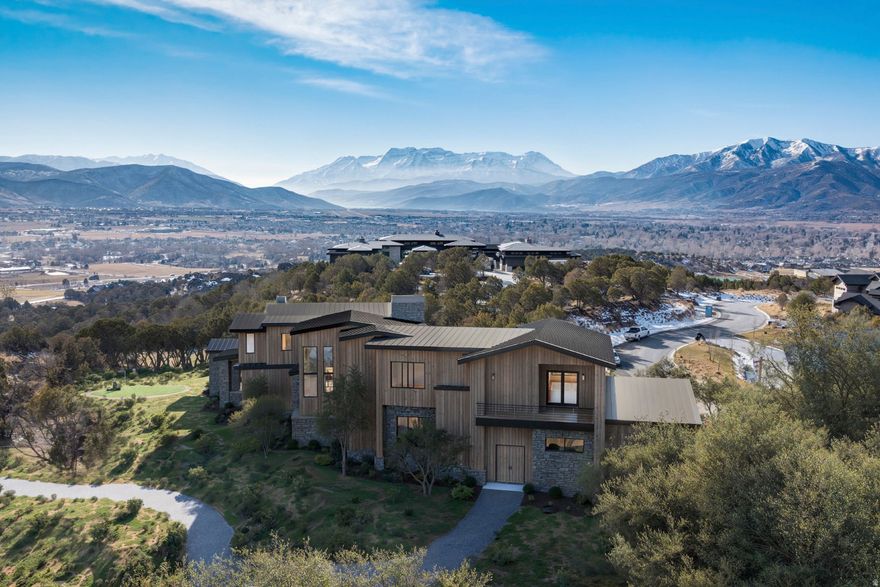 At the top of the Red Ledges, this 7,980 square foot custom residence enjoys a rare setting between the 1st tee and 18th green of the Jack Nicklaus Signature Golf Course. Surrounded by preserved open space and mature native juniper trees on all sides, the property offers an unparalleled level of privacy and sweeping views of Mount Timpanogos, Heber Valley, and Deer Valley East. Thoughtfully designed for indoor-outdoor living, the residence offers three expansive outdoor living spaces totaling over 2,000 square feet, each equipped with gas fire features and wiring for outdoor heaters. Interior highlights include a home theater, gym and wellness room, bunk room, kitchenette, three laundry rooms, and a five-car garage. The kitchen has Sub-Zero and Wolf appliances, and the home is served by four independent heating and cooling systems. Additional features include pre-plumbing for a heated driveway, an outdoor kitchen, full AV wiring. A Full Golf Membership is available with club membership deposit (not Included ) This is a rare opportunity to own a private, legacy-quality home in one of Red Ledges' most desirable locations.