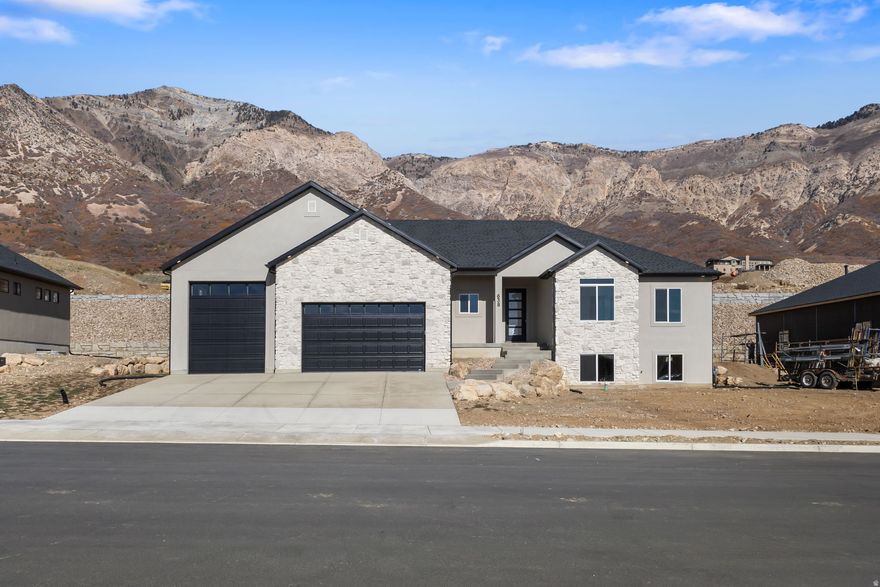 Come to the top of North Ogden and take in the stunning mountain and valley views! This brand-new rambler is filled with natural light, thanks to expansive windows that showcase the scenery and create a warm, welcoming main level. The gourmet kitchen is designed to impress, featuring a 66" fridge/freezer combo, decorative hood vented outside, gas cooktop, double ovens, and a generous walk-in pantry-perfect for both entertaining and everyday living. Enjoy 9' ceilings on both the main level and basement, and relax in the great room with a cozy gas log fireplace framed by built-in cabinetry and floating shelves. The primary suite offers a peaceful retreat with a separate tub and shower, stylish barn door, double sinks with a dedicated makeup vanity, and a spacious walk-in closet. Step outside to the 20x12 covered patio-ideal for soaking in the views year-round. The walk-out basement provides excellent potential for a future ADU, and the 4-car garage comes equipped with an EV charging outlet and epoxy floors. This home perfectly blends comfort, style, and breathtaking surroundings-don't miss your chance to see it!