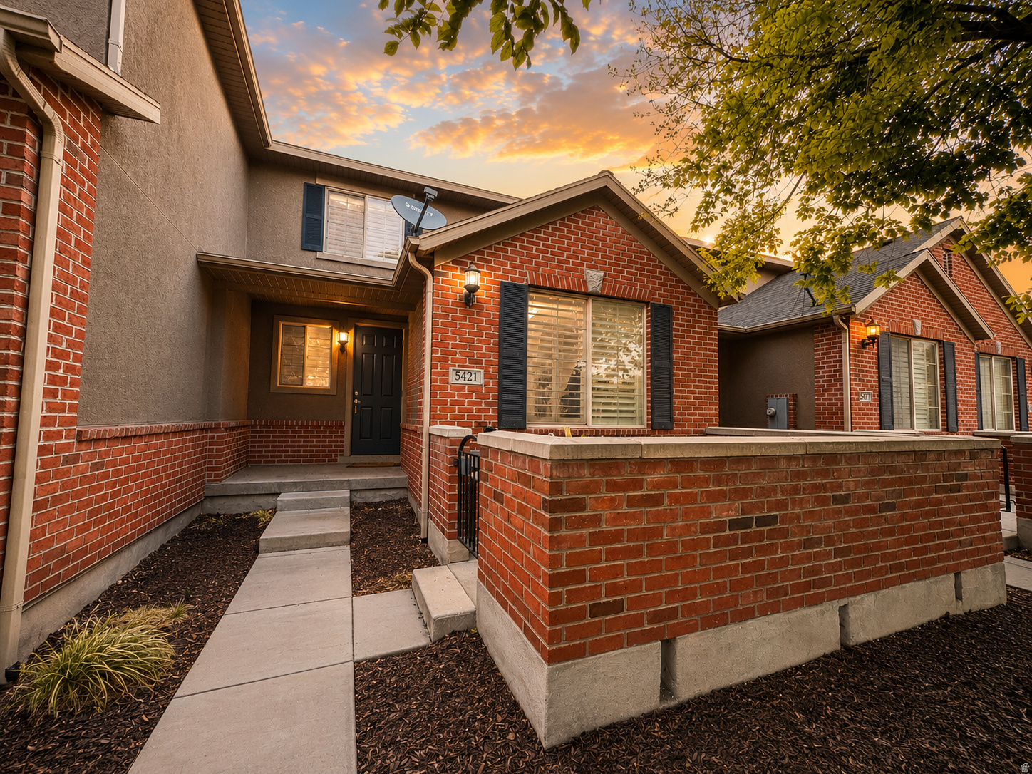 Brick and stucco exterior featuring black shutters and an entry porch light