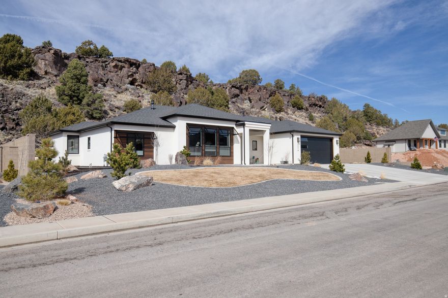 Tucked into The Canyon at Eagle Ridge, this newly built Alex Meisner custom home stands apart -- not just for its upgrades, but for the thought put into how it lives. Set on .45 acres with no HOA and no backyard neighbors, the property backs directly to protected land featuring natural caves and historic relics along the ridgeline -- preserving both privacy and views you won't find replicated elsewhere. Inside, the home feels complete from day one. Carefully chosen wallpaper and accent walls add warmth and personality throughout, while the kitchen anchors the space with high-end appliances and a bold color palette that makes the home feel inviting rather than staged. Natural light fills the 3 bed, 2 bath, 2,172 sq ft layout, creating a bright and comfortable living environment. The primary suite was designed as a retreat, featuring heated bathroom floors, while the entire home includes window coverings already installed and a water softener in place -- details often overlooked in new construction but immediately appreciated in daily living. Outside is where the property truly shines. A fully extended patio expands the living space into the backyard, framed by privacy walls on both sides of the property. Black metal awnings add architectural character and a custom finish that sets the home apart, while full paver work and landscaping complete the outdoor experience. Located in one of Cedar City's most welcoming neighborhoods, this isn't just a new build -- it's a finished home. Don't miss your chance to own a slice of The Canyon at Eagle Ridge.