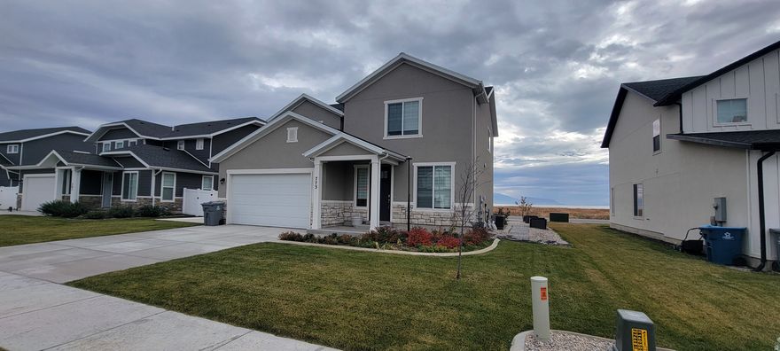 Built in 2023, this stunning 1,999 sq ft two-story home combines modern design with an unbeatable location and forever-protected views of Utah Lake and the surrounding mountains. Perfectly positioned in a quiet, family-friendly neighborhood in American Fork, you'll enjoy breathtaking, unobstructed lake and valley vistas that can never be built out. Step inside to an open-concept main floor flooded with natural light. The heart of the home is the sleek modern kitchen featuring crisp white shaker cabinetry, expansive quartz countertops, a large center island with seating, stainless steel appliances-ideal for both everyday living and entertaining. Upstairs, convenience meets comfort: all bedrooms are thoughtfully placed on the same level, with the laundry room located just steps away-no more carrying baskets up and down stairs. The spacious primary suite offers lake views, a luxurious en-suite bath with dual vanities, quartz counters,  and a generous walk-in closet.