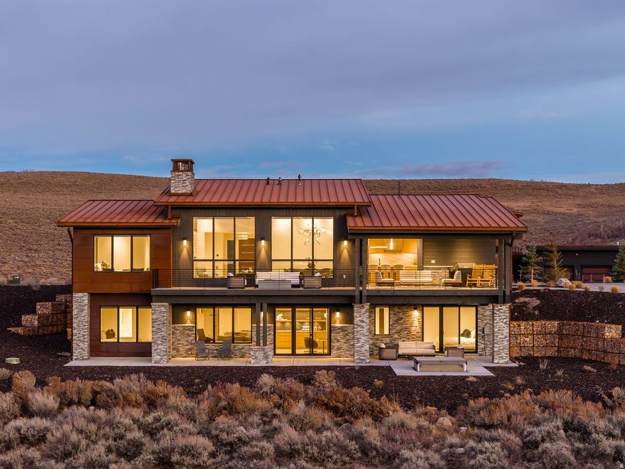 Perched dramatically above the 3rd tee of the Painted Valley Golf Course, this impeccable 5- bedroom sanctuary showcases upgrades at every turn, including a fully enhanced chef's kitchen, designer-level bathrooms, and elevated finishes throughout. The home fuses bold architectural flair with panoramic mountain and fairway views, and the location is prime- -just a leisurely stroll to the Nicklaus Clubhouse and a quick drive to the Beach Club and Dog Park. Freshly completed in late 2022, every detail was designed to amplify natural light and uninterrupted views. Thoughtfully orchestrated for seamless daily flow and spontaneous soirees, the design invites connection at every turn. At its core, a chef-inspired kitchen commands attention with its expansive island and retractable door that dissolve boundaries between indoors and out, perfect for intimate dinners or grand al fresco feasts. The airy main level unfolds into an open-concept haven, graced by a serene primary suite and a versatile secondary bedroom or office, ideal for those seeking single-story ease. Descend to the lower level for pure indulgence: a generous family room with a sleek wet bar, three more bedrooms (including a fun bunkroom for the little ones), and a dedicated game room primed for play. Practicality shines with an expansive two-car garage and a broad driveway, ensuring plenty of space for guests. A curated collection of 44 bespoke Minotti furnishings-- the pinnacle of Italian craftsmanship--are a standout feature of this home. Opulent touches abound: a sophisticated Lutron smart lighting and motorized shading system, whole-home (and outdoor) Sonos sound, and heated floors in all bathrooms. The great room's statement fireplace marries textured limestone with warm slatted oak, while the kitchen dazzles with dual- tone cabinetry and elite appliances including a Sub-Zero fridge, freezer, and wine cooler; Miele cooktop, convection oven, microwave, and warming drawer; plus dual Fisher & Paykel dishwasher drawers. Meticulously crafted and pristinely preserved, this turnkey treasure is offered fully furnished, and ready for you to claim your slice of Promontory.