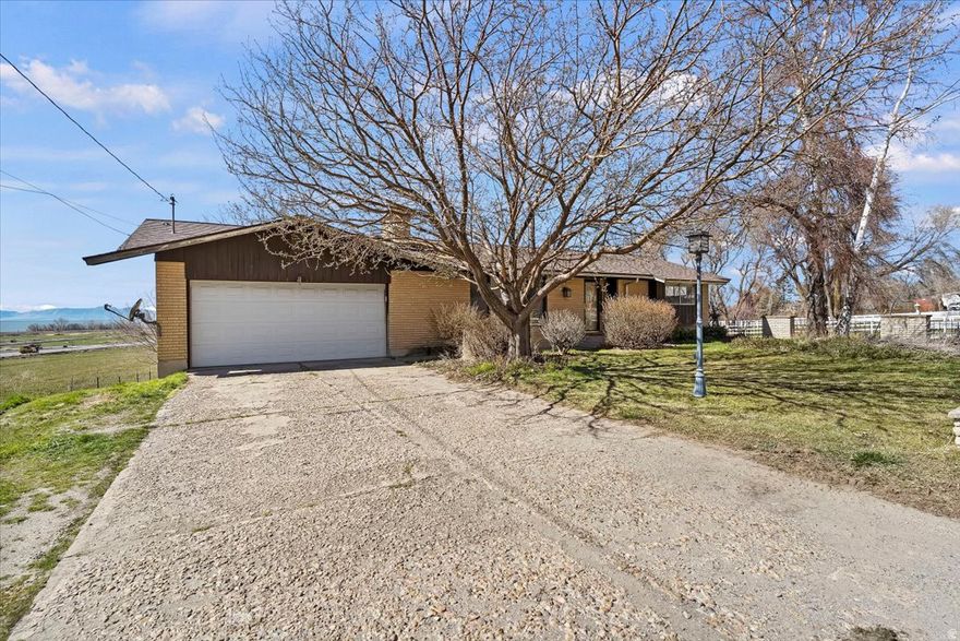 Welcome Home! Enjoy breathtaking sunrise and sunset views from both the East and West on this spacious .50-acre property. With plenty of room for animals, this yard is perfect for horses, chickens, or goats-everyone will feel right at home. This charming Rambler Ranch welcomes you the moment you step inside. The bright, open-concept family room features a cozy fireplace, creating the perfect space to gather and relax. New LVP flooring throughout the main level and fresh paint give the home a clean, updated feel. The kitchen offers plenty of space to cook and dine, complete with new stainless steel appliances, and the refrigerator is included. You will find easy access to the enclosed deck. Downstairs, the fully finished basement showcases beautiful updates including new carpet, fresh paint, cabinetry, granite countertops, and updated bathroom tile, providing additional comfortable living space. Spend your evenings unwinding in the enclosed deck, where you can enjoy peaceful views of your backyard and the waters of Willard Bay. The backyard is a true highlight, featuring fruit trees including apple, peach and nectarine ,Mulberry bushes, grape plant, strawberries, herbs, and raspberry and blackberry bushes, a large garden area, and a storage shed. Located in a quiet Box Elder community known for some of the best local produce in the state, with convenient access to schools, shopping, and a local favorite restaurant, Maddox Ranch House. Schedule your private showing today. Square footage figures are provided as a courtesy estimate only and were obtained from County . Buyer is advised to obtain an independent measurement.