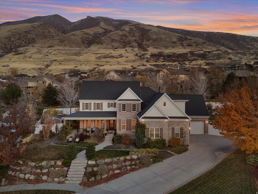 Experience refined luxury in this exceptional two-story residence, ideally located in one of Draper's most desirable neighborhoods on a quiet cul-de-sac with breathtaking mountain and valley views. Perfectly positioned on a spacious .39 acre estate lot near top-rated schools, premier shopping, dining and parks. This address boasts immediate neighborhood access to the Bunny Bradley Trail, part of the renowned trail system that Draper is famous for. The home makes a striking first impression with gorgeous new exterior siding, a new roof, new exterior trim, a welcoming wrap-around front porch that is ideal for relaxing or greeting friends. Step inside the inviting entryway, highlighted by a stunning chandelier and a view of the grand staircase, setting the tone for the elegance found throughout. The beautifully updated kitchen is designed for both everyday living and entertaining, featuring quartzite countertops, stainless steel appliances, a professional gas range with a wood-clad range hood, double ovens, an included refrigerator and beverage fridge, custom cabinets, tile backsplash, and new lighting. A charming breakfast nook with a built-in bench seat adds warmth and functionality. Truly move-in ready with fresh paint, new carpet, luxury vinyl plank flooring, plantation shutters and new Pella exterior doors on the main floor. The two-story great room is a showpiece, offering a gas fireplace, expansive windows that flood the space with natural light and a door to access the deck. The luxurious main-floor primary suite is a private retreat, complete with its own fireplace, tall ceilings, an oversized walk-in closet, and a private door leading to the covered deck. The updated primary bathroom showcases heated floors, two vanities, a soaking tub, a separate shower, quartz countertops, quartz shower surround, and stylish tile finishes. The main level also includes an elegant dining room lined with windows, a den or formal living room, a thoughtfully designed laundry and mud room with custom cabinetry, decorator tile flooring, a farm sink, and a convenient powder room. Upstairs, vaulted ceilings enhance the sense of space, with three bedrooms each offering unique charm and special features, along with two full bathrooms. Designed for flexibility, this home is ideal for big families or multi-generational living with laundry on each level and a full second kitchen in the walk-out basement. The finished basement also has a large recreation room, a gas fireplace, two bedrooms, a den, daylight windows and an entrance that leads to the patio and to the beautiful backyard. Enjoy peace of mind with a new upper-floor HVAC system installed approximately 1 year ago and a main-floor HVAC system installed about 2.5 years ago. The outdoor improvements are equally impressive including a huge RV pad, full sprinklers, a storage shed, professional landscaping, a sizable deck, covered patio, stunning landscape rock, raised garden boxes, manicured plants, mature trees, and a lush lawn. The private backyard is fully fenced, creating a serene outdoor retreat. Embrace the elevated lifestyle that Draper has to offer from exceptional outdoor recreation to premier shopping, dining, schools and entertainment.