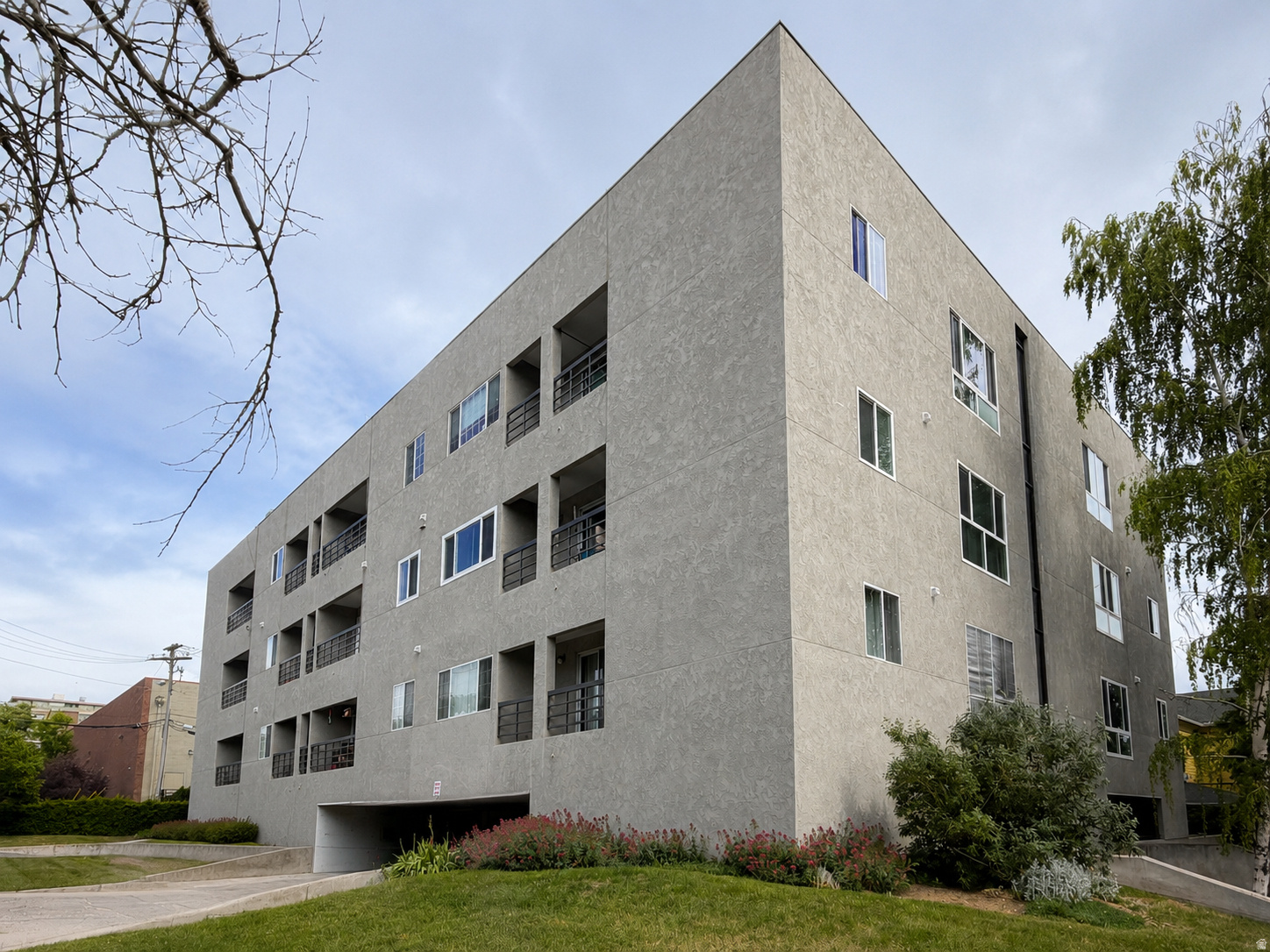 Contemporary multi-story building featuring a textured facade and private balconies with black railings