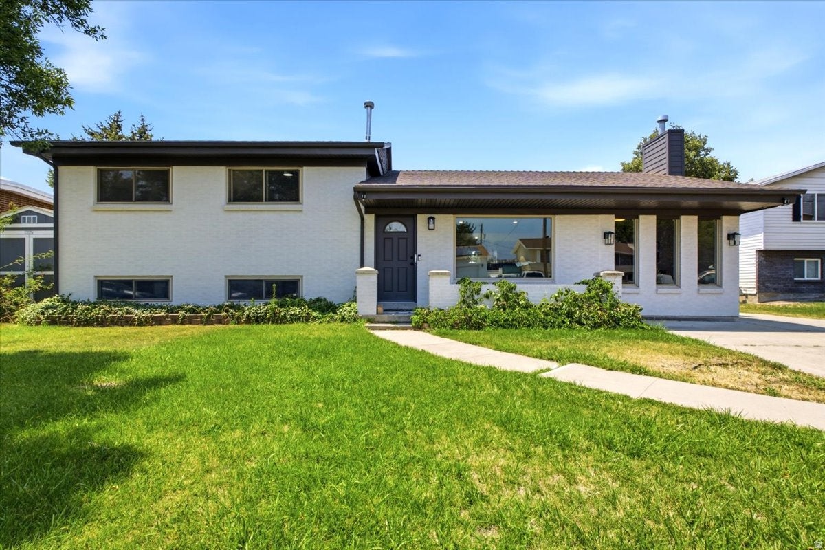 White painted brick residence featuring an expansive front lawn and concrete walkway