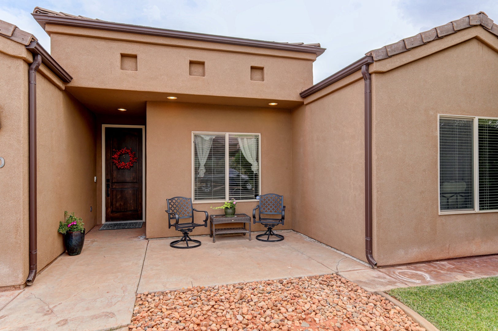 Stucco exterior with a covered entry, dark wood-finish door, and integrated recessed lighting