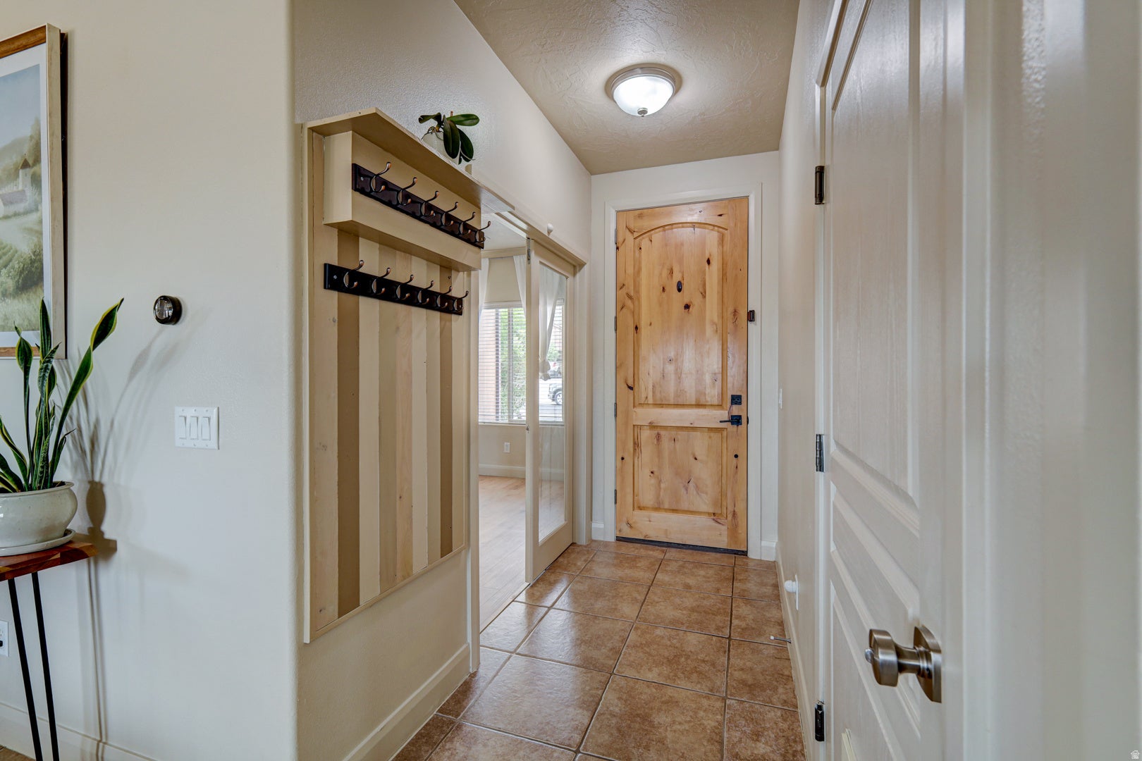 Entryway featuring tiled flooring, a solid wood entry door, and a built-in coat rack with shelving