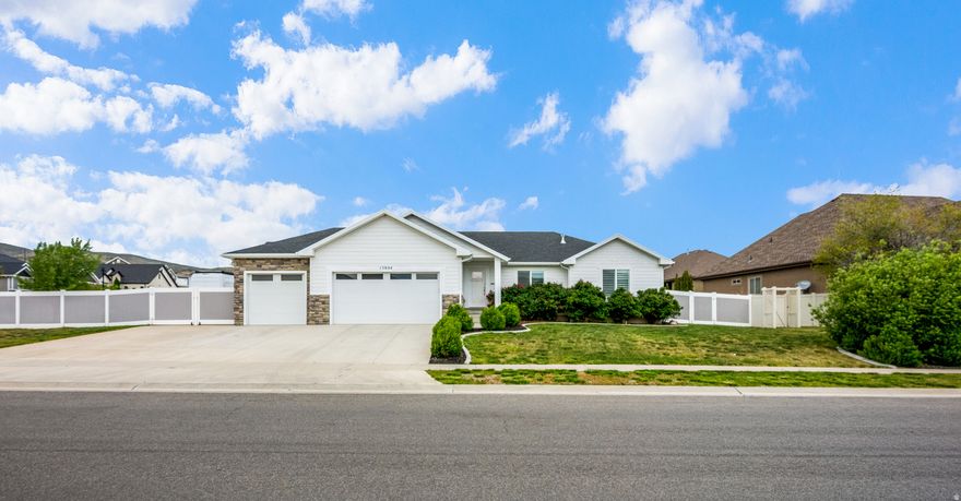 Welcome home to this beautifully designed Bluffdale rambler, where spacious living and exceptional design come together on a large corner lot. Vaulted ceilings and an open-concept floorplan create a bright, inviting atmosphere, while fireplaces in both the upstairs and downstairs living rooms add warmth and character throughout the home. The kitchen features white shaker-style cabinetry, quartz countertops, stainless steel appliances, and designer pendant lighting that elevate the space with timeless style. Designed for convenient main-level living, the home offers three bedrooms and two full bathrooms upstairs, including a spacious primary suite with a walk-in closet, dual vanity, separate tub, and shower. The fully finished basement expands the living space with a large family room, dry bar/kitchenette, two additional bedrooms, a full bathroom, versatile den space, and a second laundry room complete with a charming dog washing station. Outside, the oversized corner lot offers abundant space for RV parking, trailers, toys, and outdoor entertaining. A pergola-covered gathering area creates the perfect setting for relaxing evenings and hosting friends and family. Thoughtfully designed inside and out, this Bluffdale home offers the space, flexibility, and comfort to fit every stage of life.