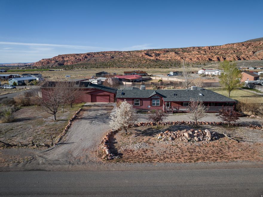 This beautifully renovated three-bedroom, three-bathroom home sits on 1.26 acres with views of the red rocks and La Sal mountains. The property includes a multitude of desirable features, including a Trex veranda wrapping around the home, a large 6 car shop/garage, a solar system installed in 2017, and a spacious, grassy backyard with mature trees. The sizable kitchen with bar seating, granite countertops, pull-out shelves, and an oversized island has been beautifully updated and the roof, windows, and skylights have all been recently replaced. You'll enjoy the instant hot water with the recently installed on-demand tankless water heater. The home features two master bedrooms with connecting bathrooms, one being exceptionally large with a lounging/exercise area bathed in natural light and a new master bath. There is an office/den that could be easily made into a fourth bedroom. The gravel circle drive offers plentiful parking as well as two concrete parking pads and the oversized garage/shop. The garage is a two car detached garage with a large storage/exercise room, and a door connects it to an extra tall four-car shop featuring a small bathroom, a sink, a workbench, and a vehicle lift. Property has a well, a water right, and a septic tank.