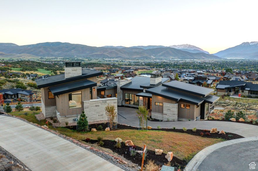 Nestled in the heart of the prestigious Red Ledges community, this custom designed home blends modern architecture with breathtaking natural beauty. From every room, enjoy panoramic views, including direct vistas of Mt. Timpanogos, creating an unparalleled living experience. The open-concept living room is a masterpiece, bathed in sunlight with soaring ceilings and a stunning fireplace that anchors the space. Expansive windows throughout the home bring the outdoors in, framing the majestic Heber Valley. Step onto the spacious decks on both levels to seamlessly transition between indoor and outdoor living. The kitchen is a chef's dream, featuring high-end appliances, double dishwashers and a spacious pantry with a convenient pass-through window. Oversized windows infuse the space with light and offer breathtaking mountain vistas, making every meal an experience. The main-level primary suite is a retreat unto itself, located on the quiet north corner of the home. Vaulted ceilings, a spa-like bathroom with heated floors, and a walk-in closet complete this sanctuary. Additional main level amenities include a beautifully tiled mudroom connecting the three-car garage and a large laundry room. The lower level is designed for hosting and relaxation, featuring a large family room, a secluded theater room, and a bunk suite with four bunks that open to a full bedroom. A dedicated entertainment fridge adds convenience, making this space perfect for gatherings. The upper level boasts a unique office space and a private en-suite bedroom, offering flexibility for guests or remote work. This home exudes elegance with its thoughtful details, including two HVAC units, heated floors in the bathrooms, pantry and laundry room. Whether you're enjoying the  the views, entertaining, or simply relaxing, this residence offers the perfect balance of comfort and sophistication in a captivating mountain setting. Live where luxury meets nature - welcome to your dream home in Red Ledges.