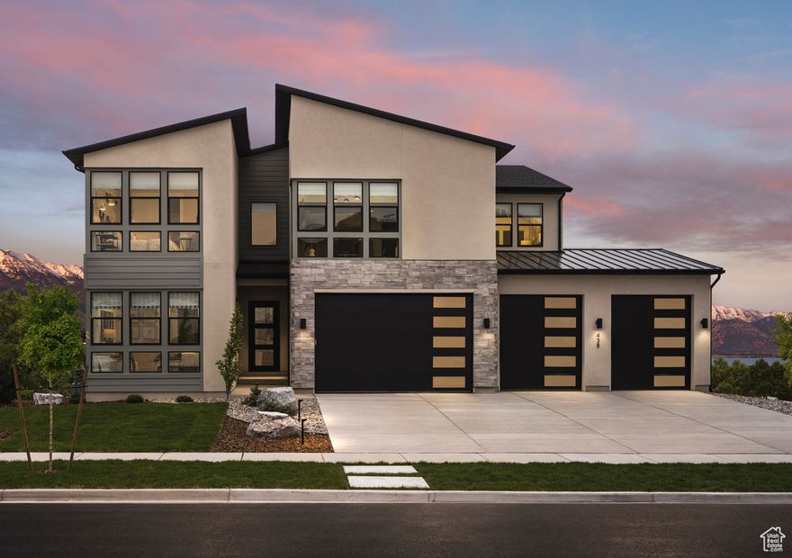 Experience luxury and comfort in this fully decorated model home, showcased in the Utah County Parade of Homes. Situated on an oversized lot, the outdoor space is designed for relaxation and entertaining, featuring a cozy gas fireplace, hot tub, and outdoor cooking area. This Tuscarora Mountain Modern features a 4-car garage and a sleek, contemporary design. Positioned to capture stunning mountain and lake views to the east and south, the covered deck provides the perfect setting for morning coffee or evening relaxation Inside, soaring 20-foot ceilings in the 2-story family room create a grand and airy atmosphere, anchored by a striking fireplace. Thoughtfully designed with custom paneling, wallpaper, and built-in cabinetry-all unique to this home-every detail reflects elevated craftsmanship. The primary suite is a spa-like retreat, complete with a soaking tub for ultimate relaxation. Designed for flexibility and comfort, the finished walkout basement includes a stylish dry bar. Five of the six bedrooms feature en-suite bathrooms, offering privacy and convenience for family and guests alike. This rare opportunity to own a Parade of Homes masterpiece won't last-schedule your private tour today.