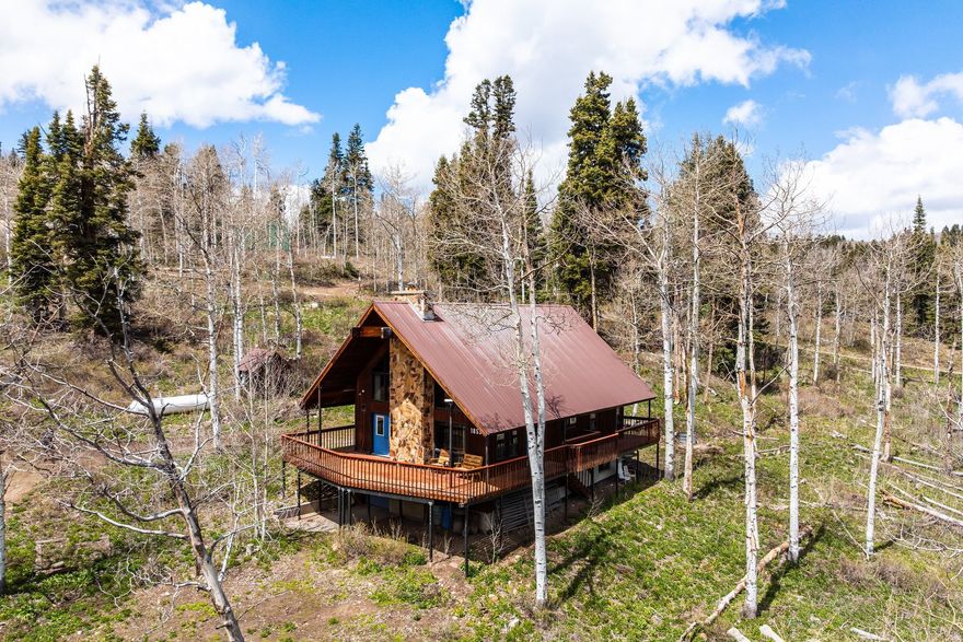 Tucked into a quiet seasonal loop in Pine Meadows and set on two acres surrounded by mature trees, this family-owned cabin offers a rare opportunity for a private mountain retreat. Built in 1989 and held by the same family, the property has been thoughtfully cared for and carries a sense of history that is felt the moment you arrive. If walls could talk, they would tell stories of summers filled with laughter, reunions, and time well spent in the mountains. The cabin features five bedrooms, including a spacious bunk room designed for gathering, along with two and a half bathrooms. Expansive picture windows bring in natural light and frame the surrounding trees, while wood ceilings and trim create a warm, classic cabin feel. A wood burning stove serves as the heart of the home, offering both ambiance and function for cooler mountain evenings. Outdoor living is just as inviting, with a full wraparound deck that encourages relaxing, entertaining, and taking in the peaceful setting. The two-acre parcel provides privacy and seclusion, along with ample space for parking, recreation, and future enjoyment. A fire pit sets the stage for evenings under the stars, while the one car garage and detached shed offer convenient storage for gear and seasonal items. Equipped with power, propane, and a septic system, the property is well suited for summer use and offers a true escape from the pace of everyday life. In the winter months, access is available by snowmobile or tracked vehicle, just a short distance off the plowed route, adding to the cabin's sense of seasonal adventure. Whether you are continuing a legacy or starting your own, this is a place where lasting memories are made.
