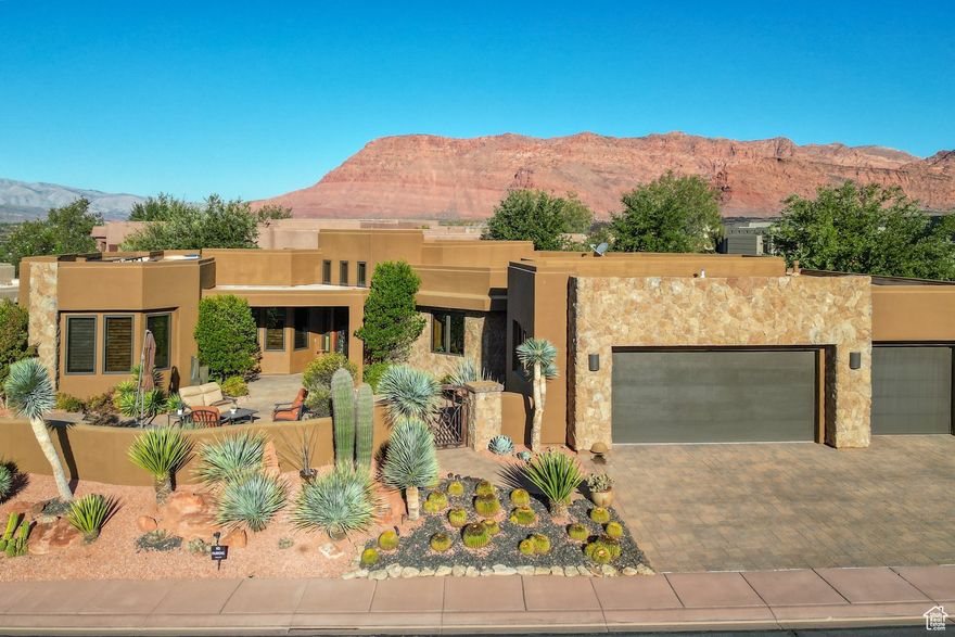 Welcome to this stunning 2011 Parade Home in the Cliffs at Snow Canyon. The entry sets the tone with a custom metal courtyard gate, stone water feature, paver courtyard, and striking glass, wood, and iron front door. Inside, the living room features large windows with red rock views, a Venetian plaster fireplace, backlit recessed ceiling detail and built-in entertainment center with Hunter Douglas electric blinds. The Chef's Kitchen is a highlight with Thermador appliances, granite countertops, a copper range hood and copper sink, island bar, custom backsplash, and built-in refrigerator, oven and dishwasher. The dining area sits beside large windows that bring in natural light and views. The primary suite offers patio access, a Venetian plaster fireplace, and a spa bathroom with double vanities, jetted tub, walk-in shower, vanity table, Kohler fixtures, and a custom walk-in closet with skylight, drawers, and shelves. Two guest bedrooms each include their own en-suite bath and walk-in shower. An office with built-in bookcases and a desk with drawers add function and versatility. Throughout the home, you'll find travertine floors, wood baseboards, solid wood doors, shutters, and wood window frames, as well as convenient bedside lighting controls in each bedroom. A skylight brightens the garage entry, while the oversized 3-car garage includes epoxy floors, storage cabinets, a sink, and countertop. Outdoor living shines with a large covered paver patio with fire pit, built-in outdoor kitchen with BBQ grill, gas cooktop, sink, and storage. The exterior features recently painted stucco and stone accented with lichens, and blends beautifully with the desert setting. The home also features a security system, solar panels, and Samsung battery walls. Owners enjoy access to the community pool, tennis courts, and clubhouse, with the option to join Entrada Country Club Social Membership. Furniture package available.. The home is a short drive to the sheer massive cliff walls of Zion National Park, the hoodoos of Bryce Canyon National park, or the North Rim of The Grand Canyon. There is no place like it. You can drive to Tuacahn, Snow Canyon State Park, and Fire Lake within 5 minutes. Enjoy nearby hiking, biking, and outdoor adventures or any of the 4 amazing large reservoirs and thousands of recreational public acres for the adventurous at heart. Scout cave can be found on the cliffs just above the home. The region is also known for its internationally renowned golf courses that recently hosted the PGA tournament and will soon host the LPGA. Saint George is also the host for many events such as the Ironman, Red Bull Rampage, and the Saint George Marathon. All information herein is deemed reliable but is not guaranteed. The buyer is responsible to verify all listing information, including square feet/acreage, to the buyer's own satisfaction.