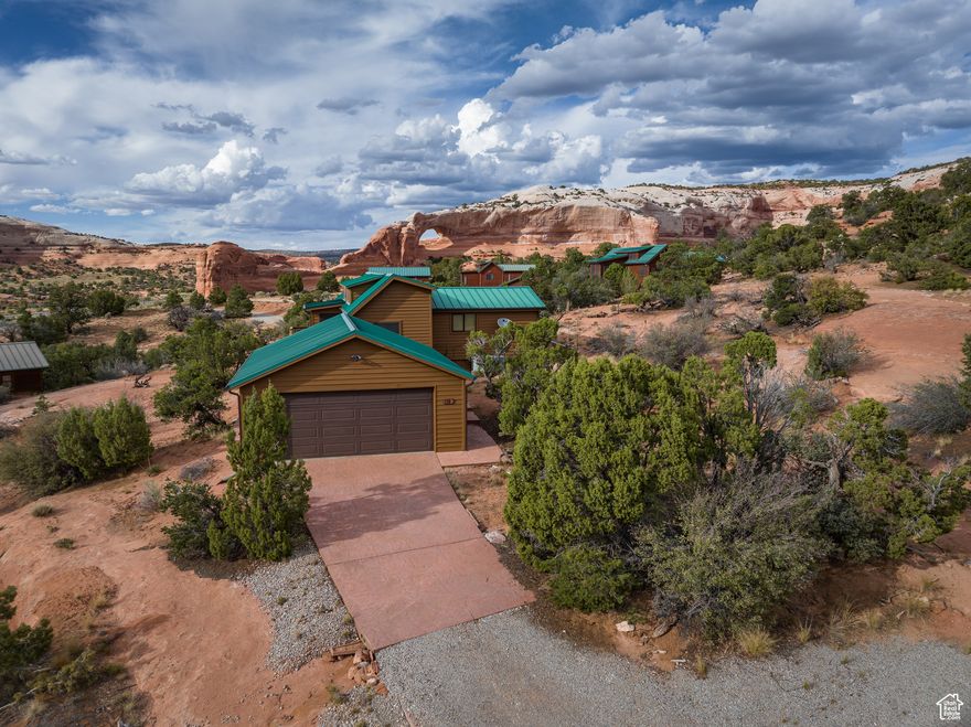 WILSON ARCH COTTAGE. Truly a fairytale cottage at Wilson Arch, at the base of a majestic sandstone buttress, complete with a waterfall when the rain comes through. This sweet property has a wraparound deck for your sunset enjoyment, with views of Wilson Arch, the Abajo Mountains, and Canyonlands National Park on the horizon. The cottage has two bedrooms, one full bathroom, and a loft for guests, storage, or a playroom.  Wonderful finishes, including custom cabinetry, tongue and groove ceilings, Corian countertops, and it has the furnishings included! The cottage sits on a full 1/3-acre lot and is equipped with an oversized garage. The Wilson Arch Community is centrally located to incredible recreation, with four-wheel drive trails out the back door, set between two National Parks, and a quick trip to Indian Creek climbing.  Do it all, see it all, then come back to your little care-free retreat! Offering potential Seller Financing.