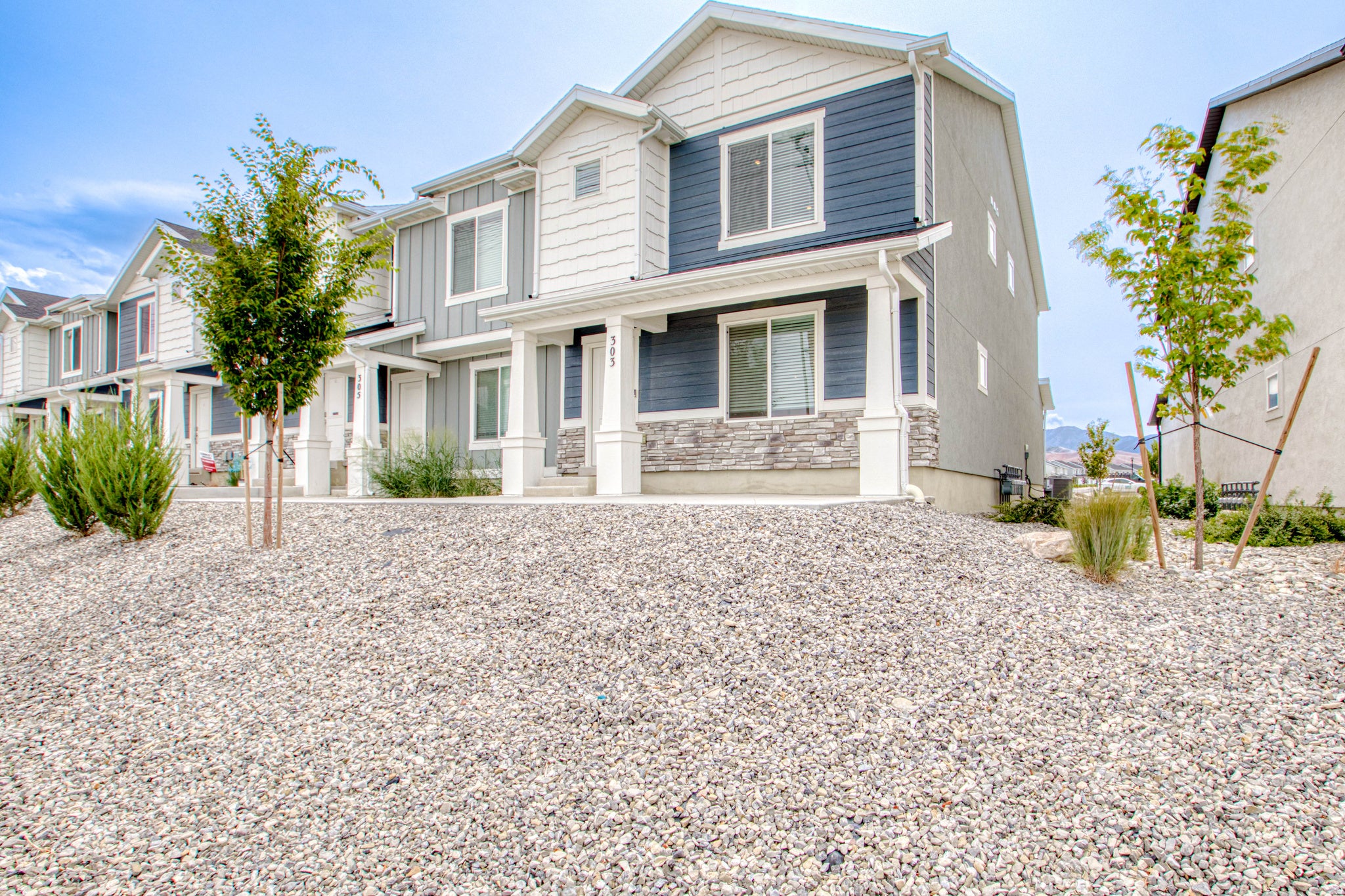 Contemporary multi-level residence featuring a covered entry, columned porch, and stone facade accents